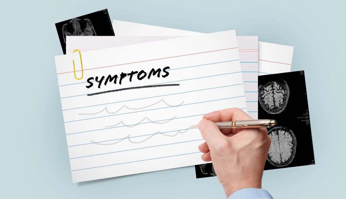 Writing out the list of symptoms you've faced can help you prepare for your Parkinson's disease doctor appointment A hand with a pen writing down a list of symptoms on an index card with brain scan images underneath the card