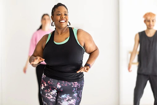 Smiling african woman enjoying dancing at fitness studio