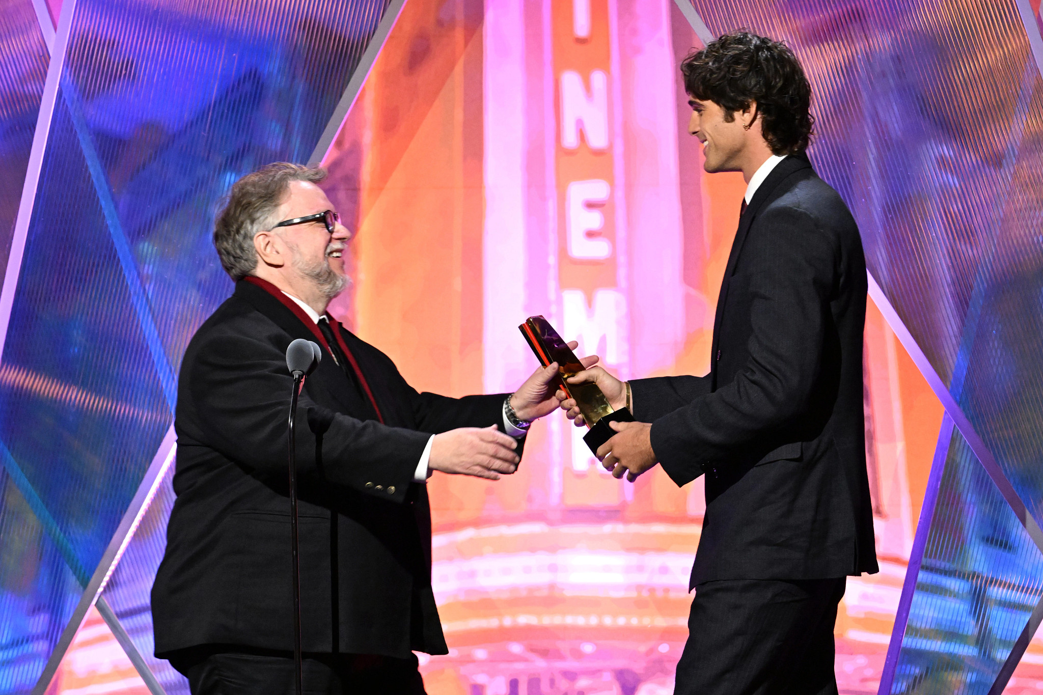 Guillermo del Toro accepting an award onstage with jacob elordi