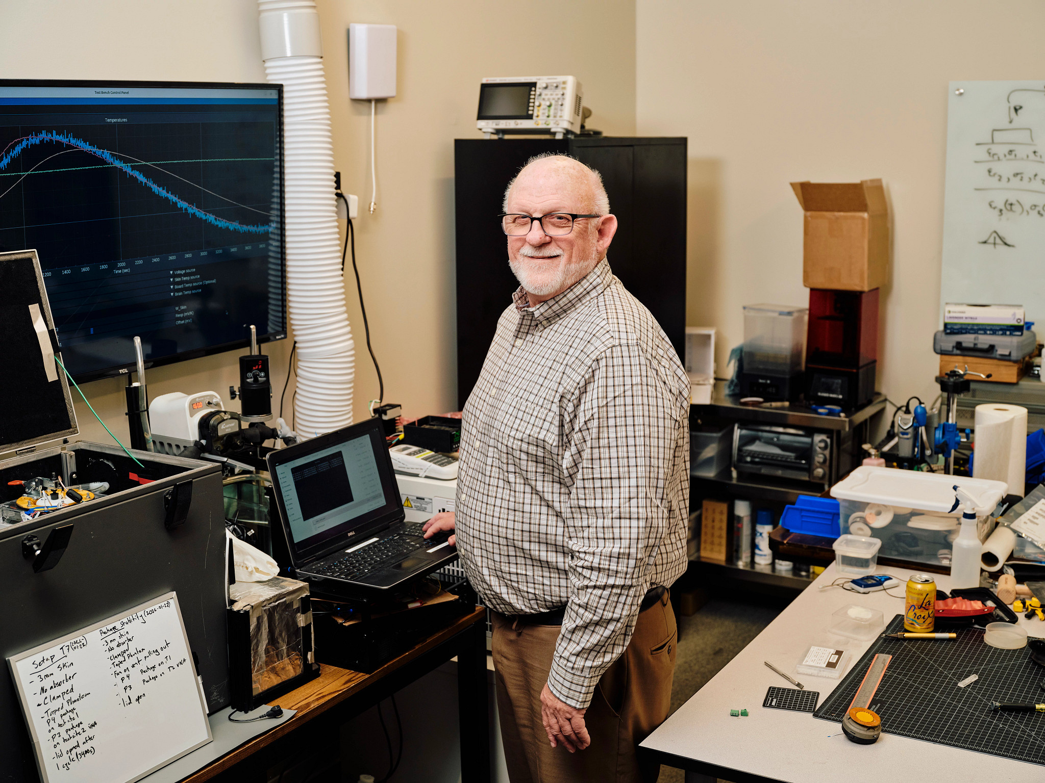 a man standing in an office next to a laptop