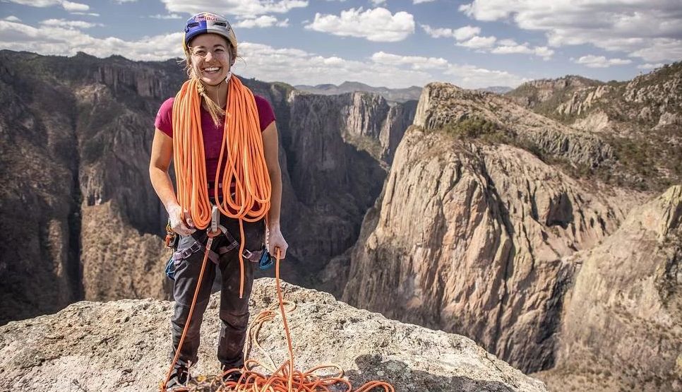 Sasha DiGiulian standing on a mountain with orange rope surrounding her neck