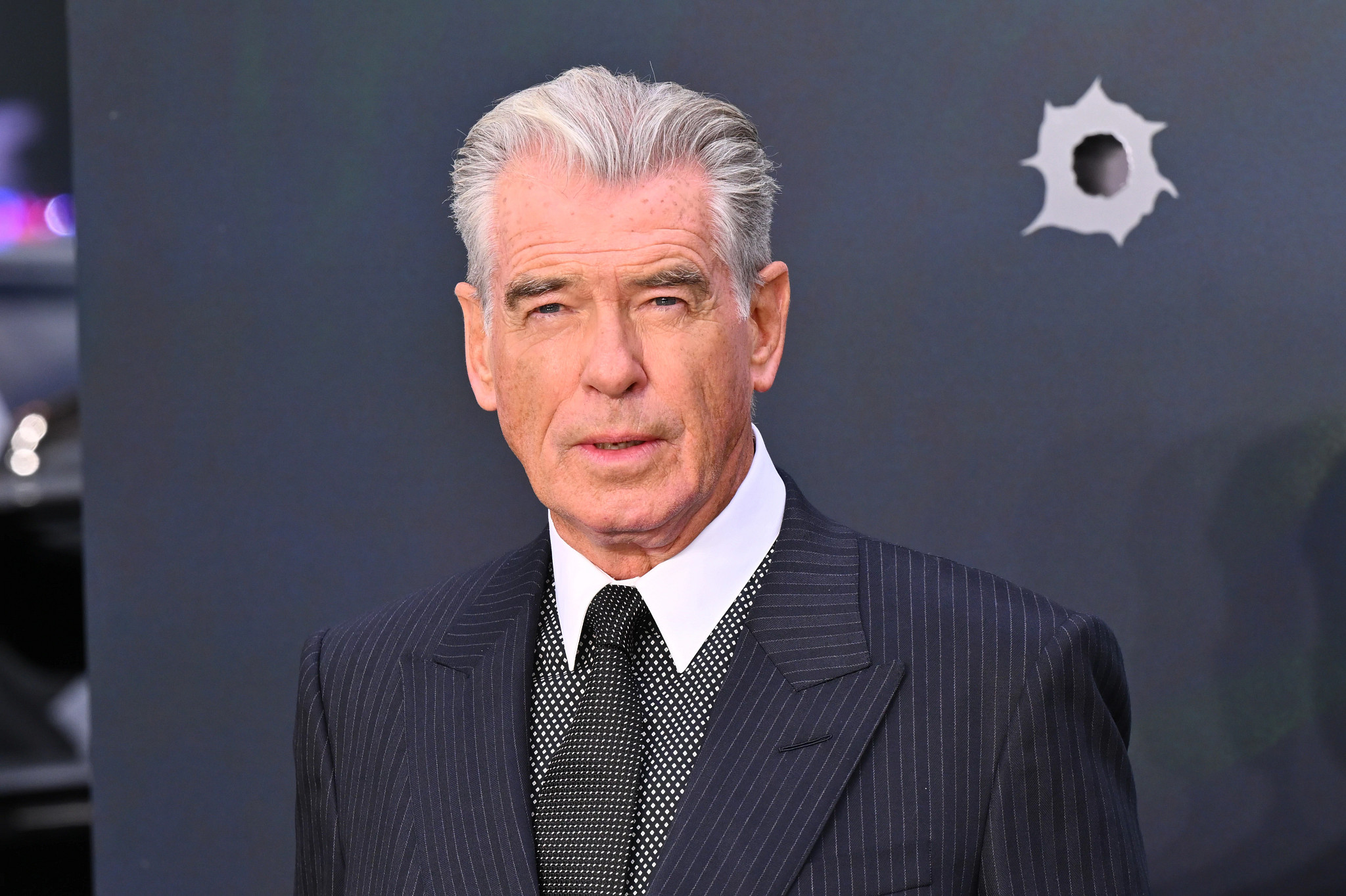 Pierce Brosnan wearing a suit jacket and tie.