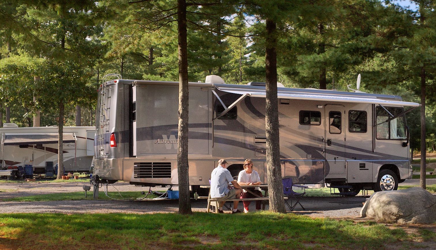 Normandy Farms people sitting at a table outside of an RV at a campsite