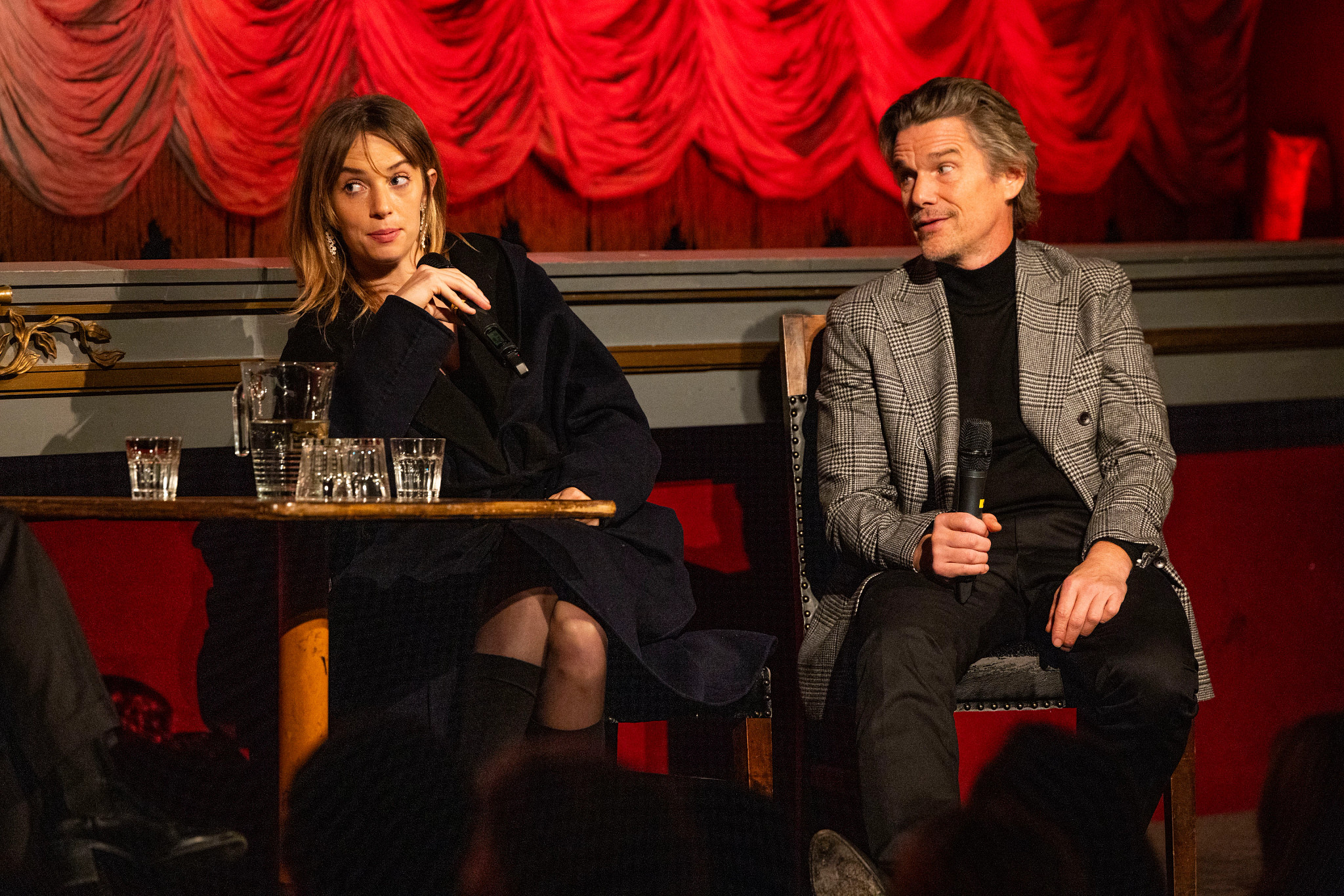 maya hawke and ethan hawke seated while holding microphones