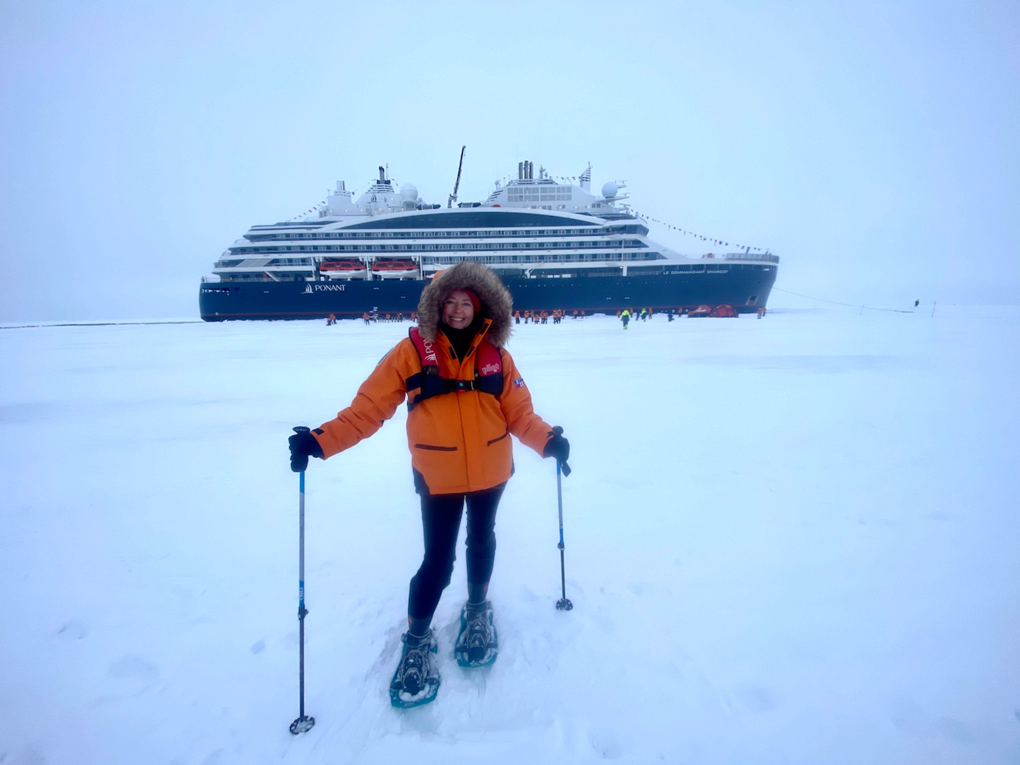 a woman smiling and posing while at the georgaphic north pole