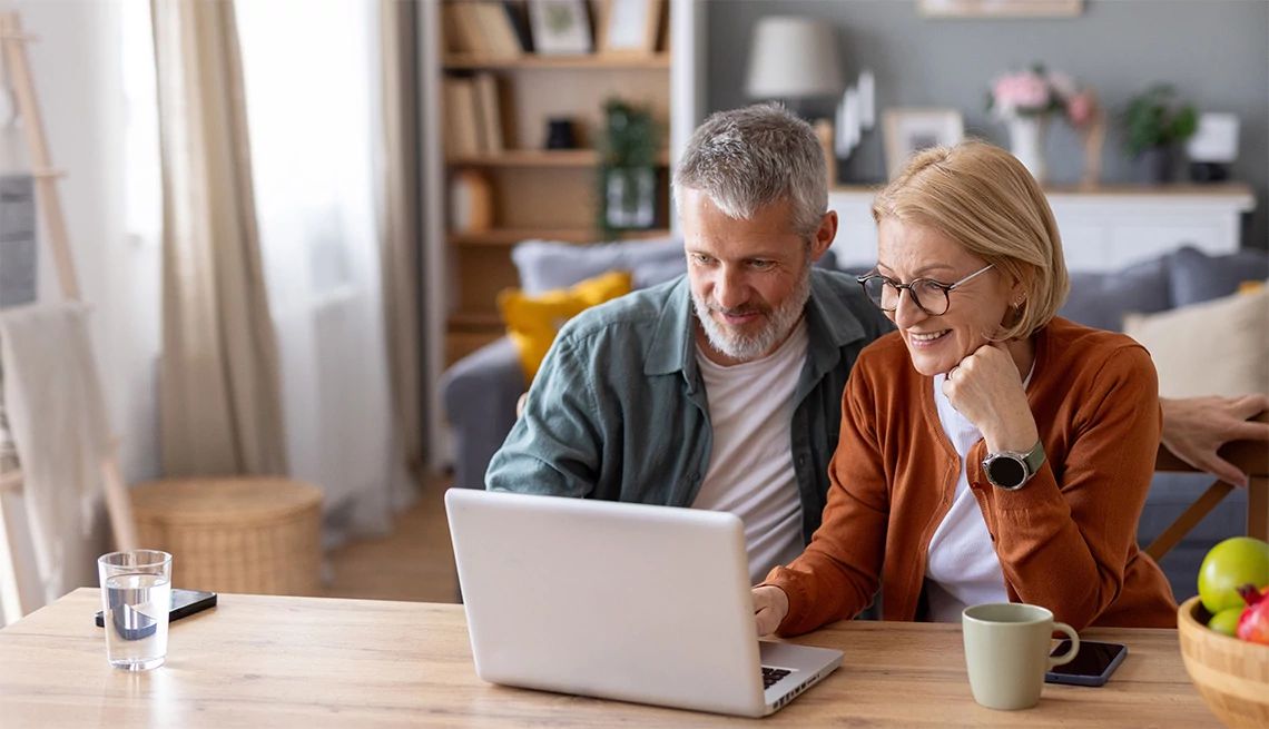 Man and woman in their 50s looking at AARP Medicare Plans from UnitedHealthcare on their laptop in the kitchen