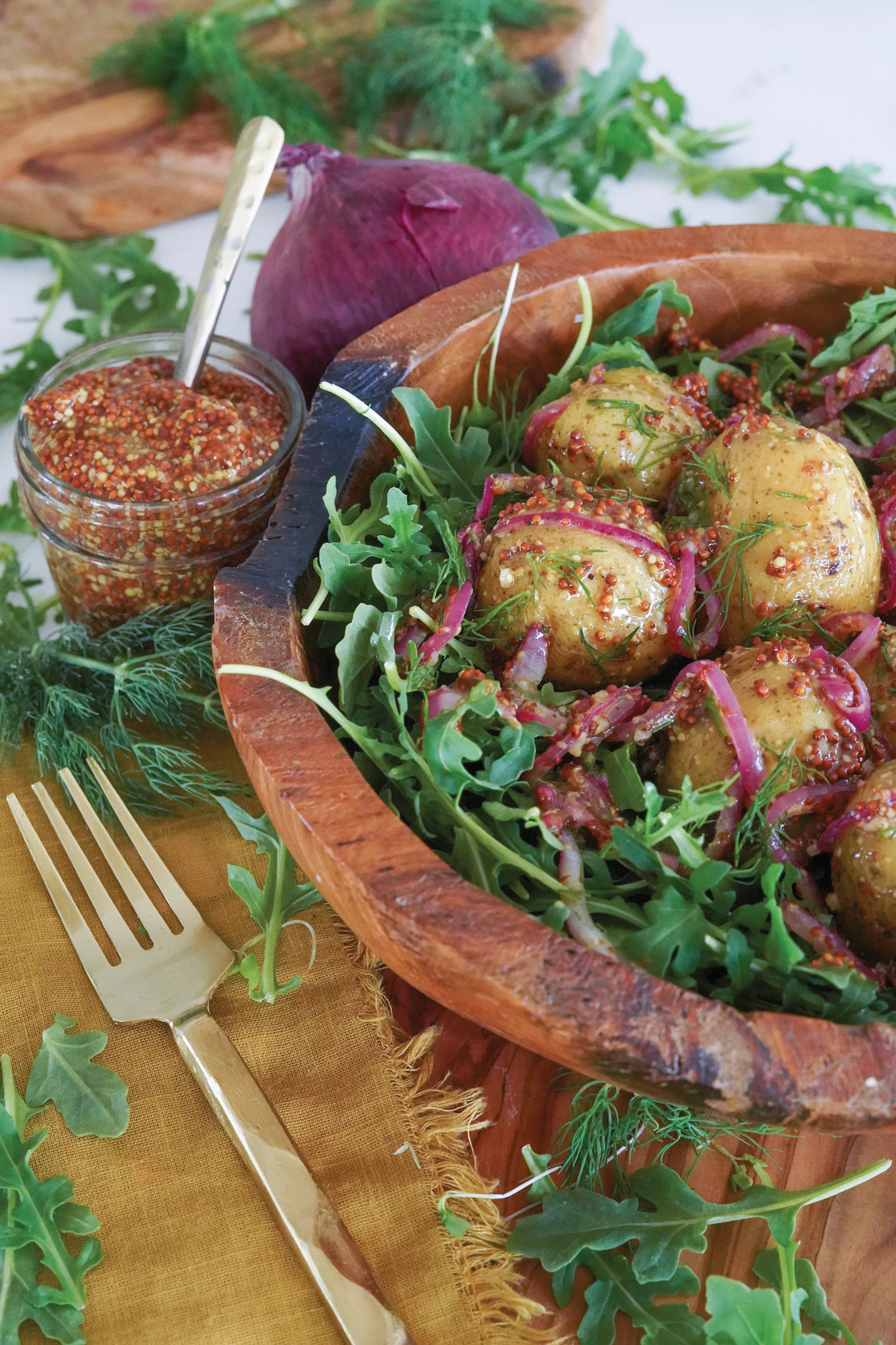 Potatoes and greens in wooden bowl