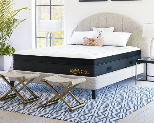 The Nolah Evolution mattress in a white bedroom with a blue rug.