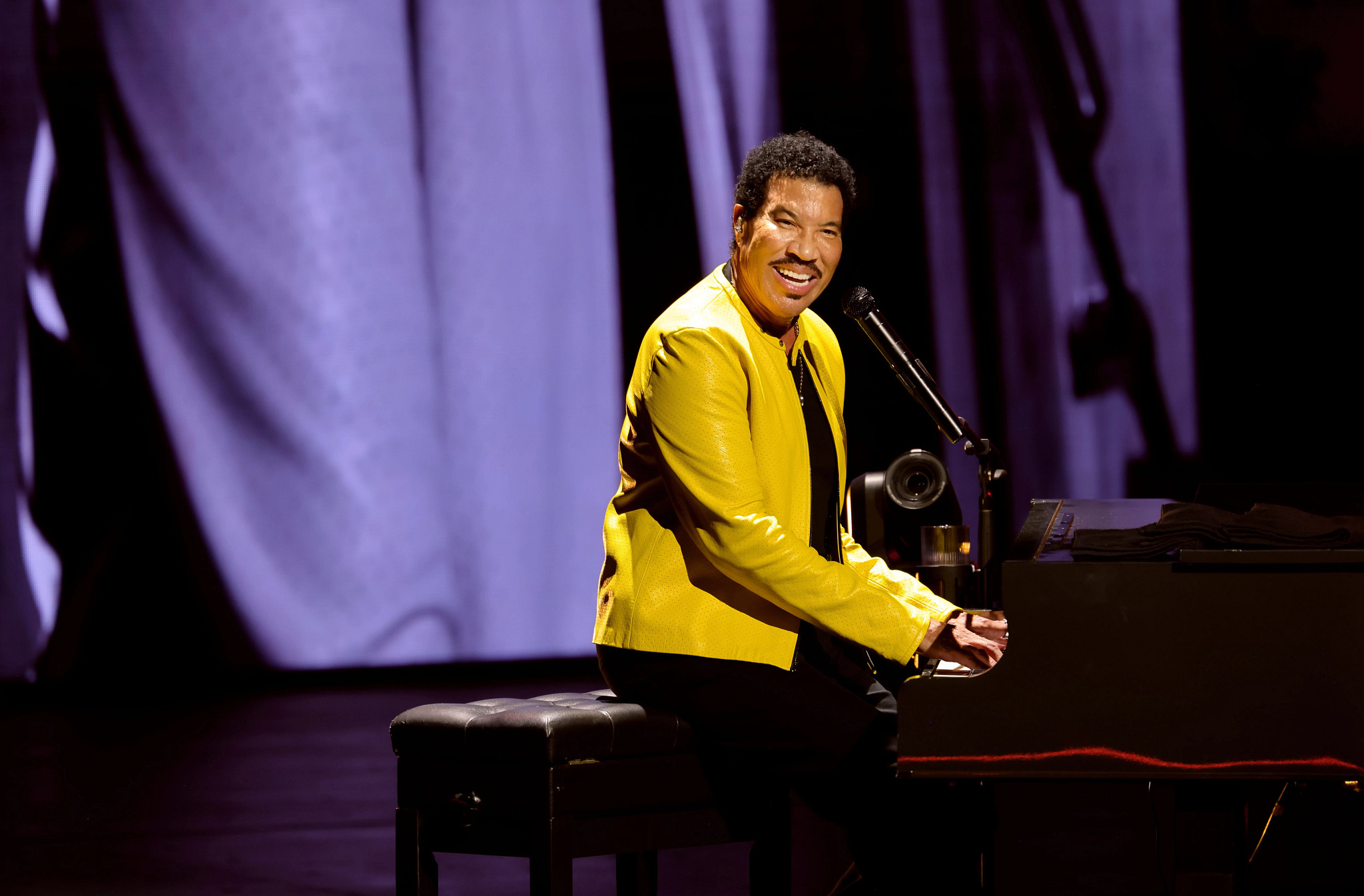 Lionel Richie playing a piano while performing onstage