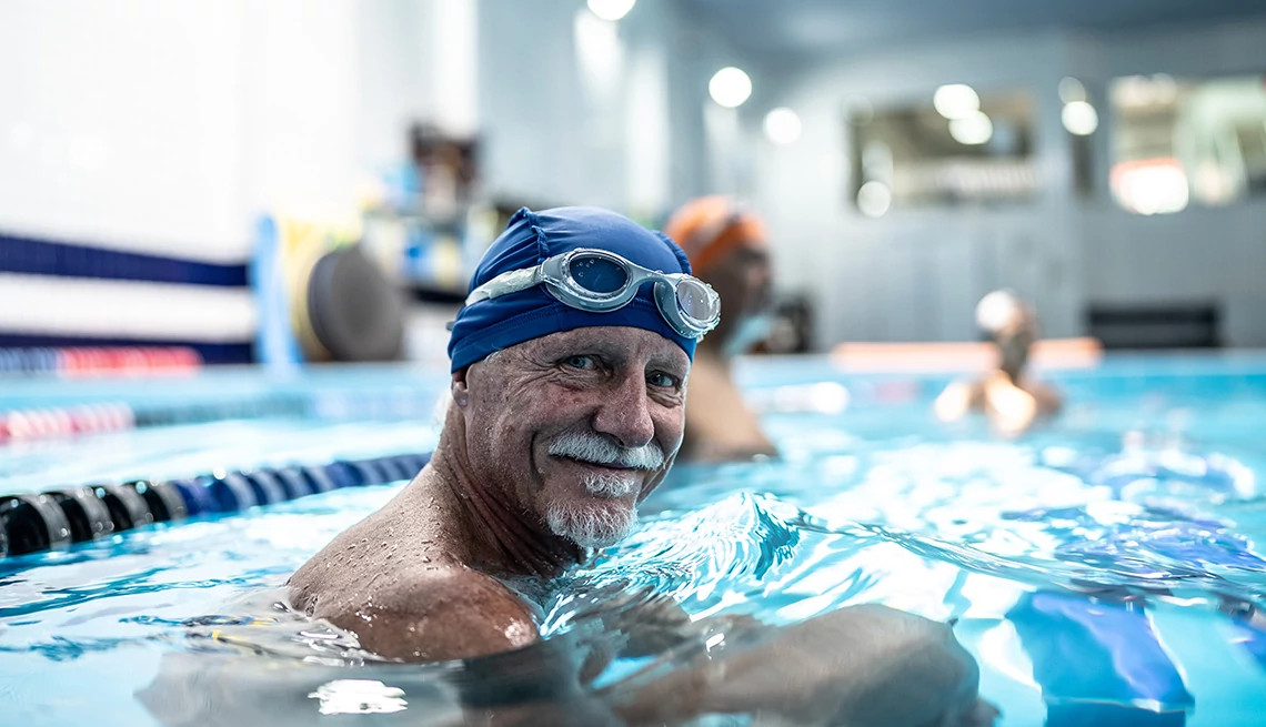 A man with a swimming cap and goggles in an indoor pool