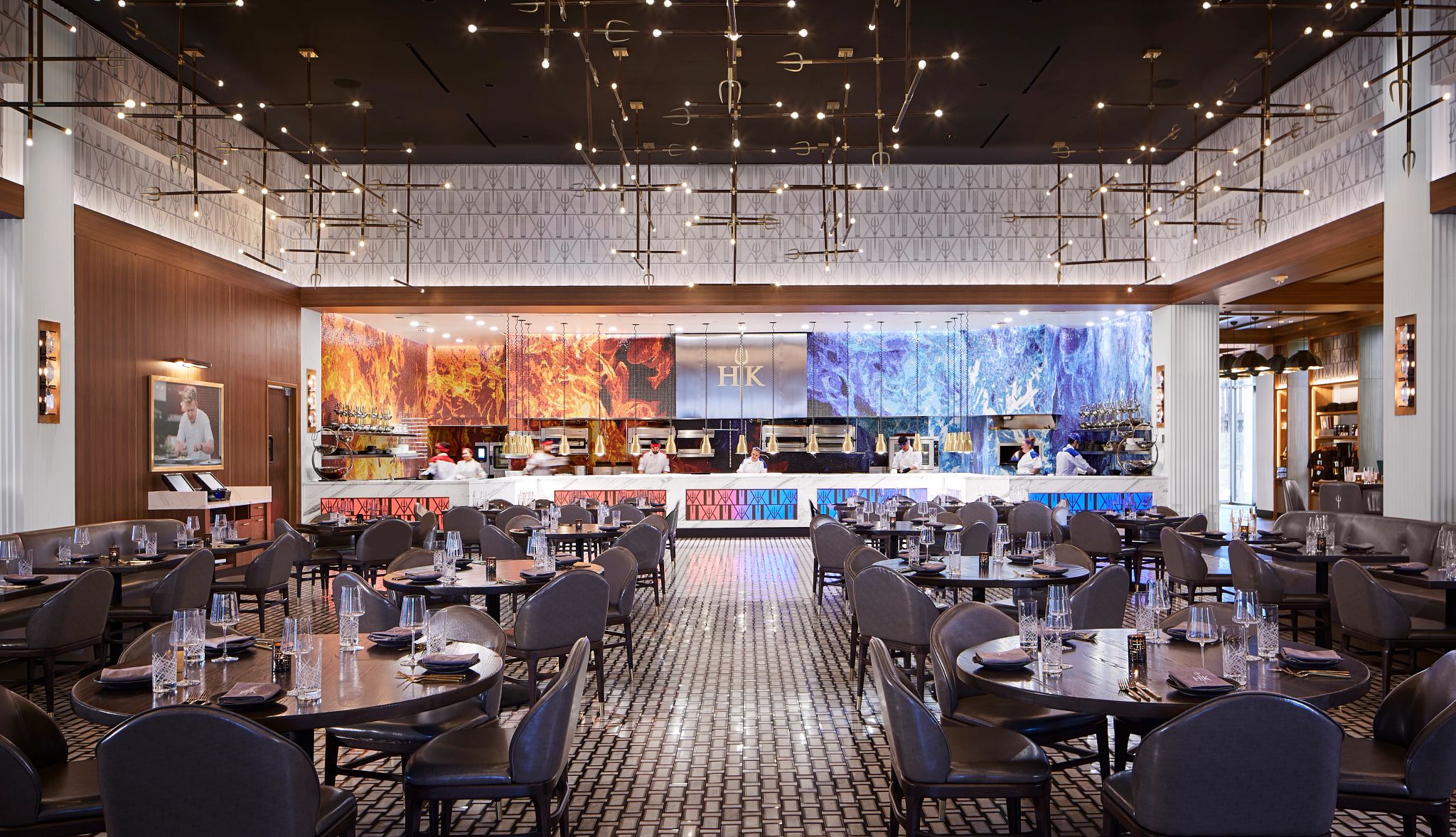 Go for first-class dining Inside of Hell's Kitchen Restaurant showing tables and employees back in the kitchen; picture of fire on the wall on left and picture of blue water on the wall on right