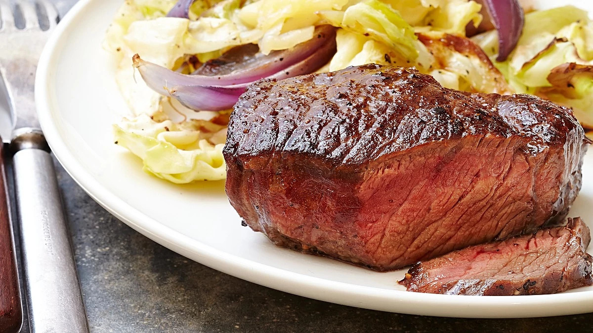 A close-up view of steak with cheddar roasted cabbage on a plate