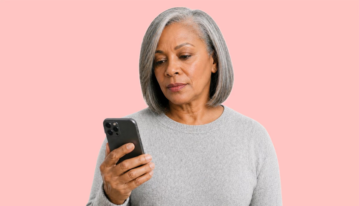 Woman with a concerned look on her face looking at her cell phone after receiving a scam text message