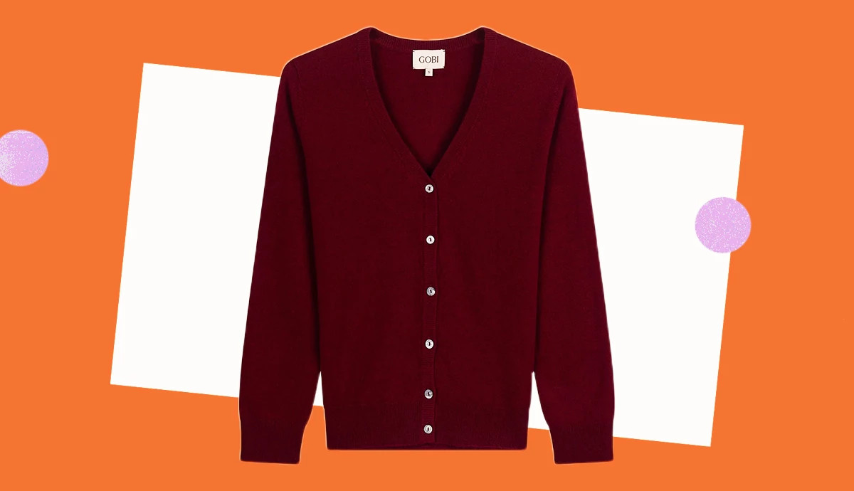 a dark red v neck cardigan on a colorful orange and white background