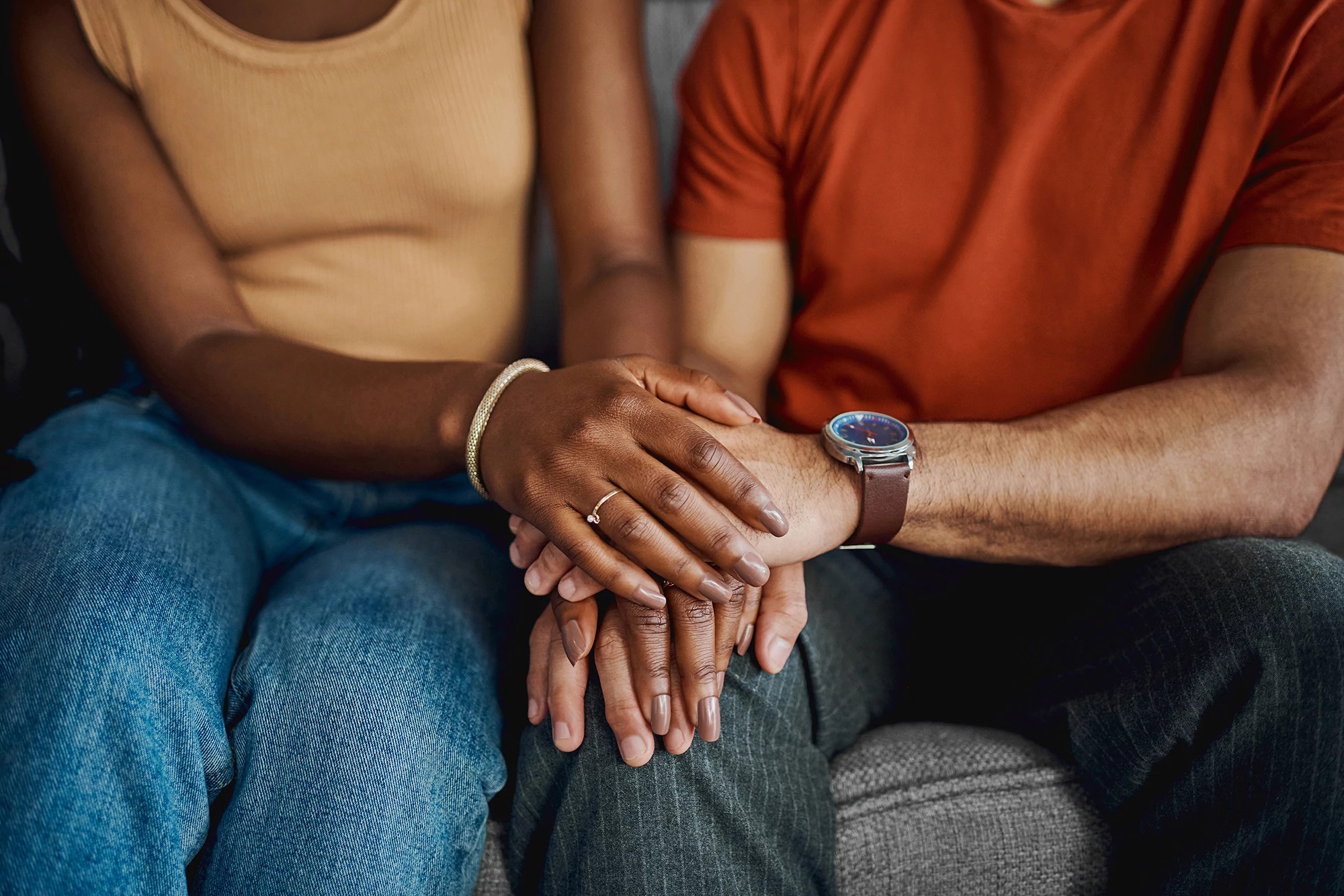 Close-up  couple sitting together on the sofa at home and holding hands
