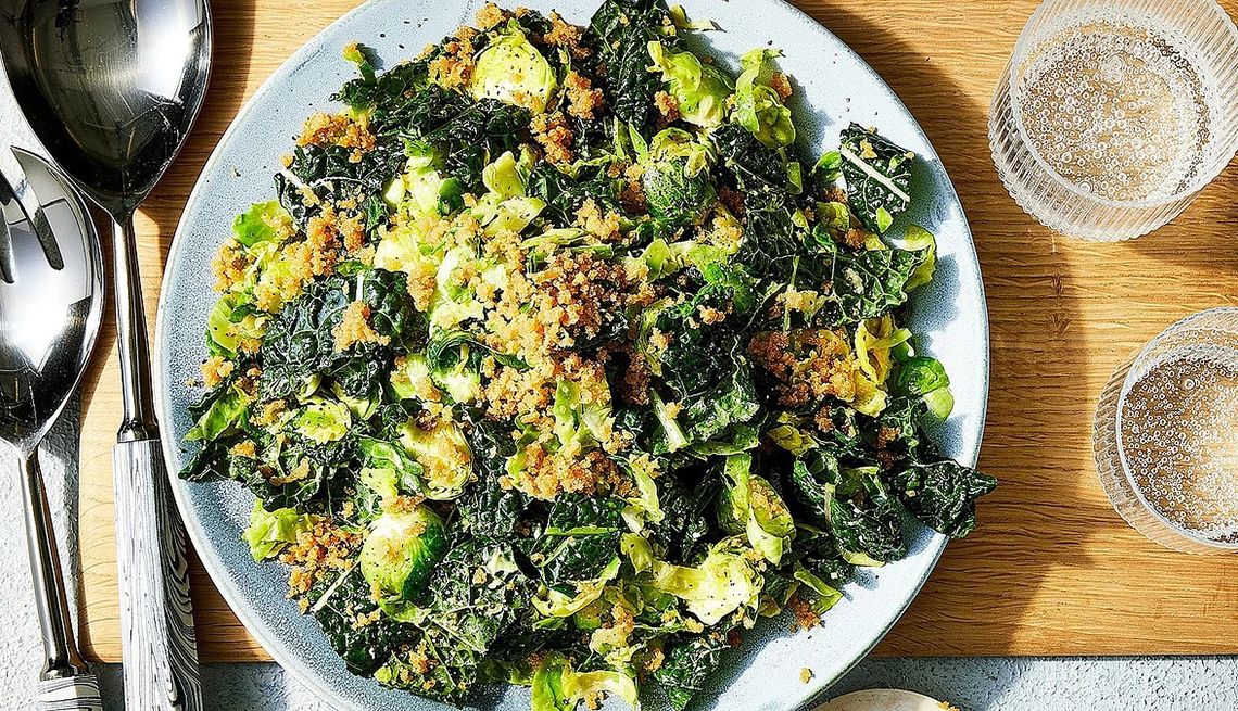 Kale and shaved Brussels sprouts salad with avocado Caesar dressing A close-up view of a kale and shaved Brussels sprouts salad with avocado Caesar dressing on a plate