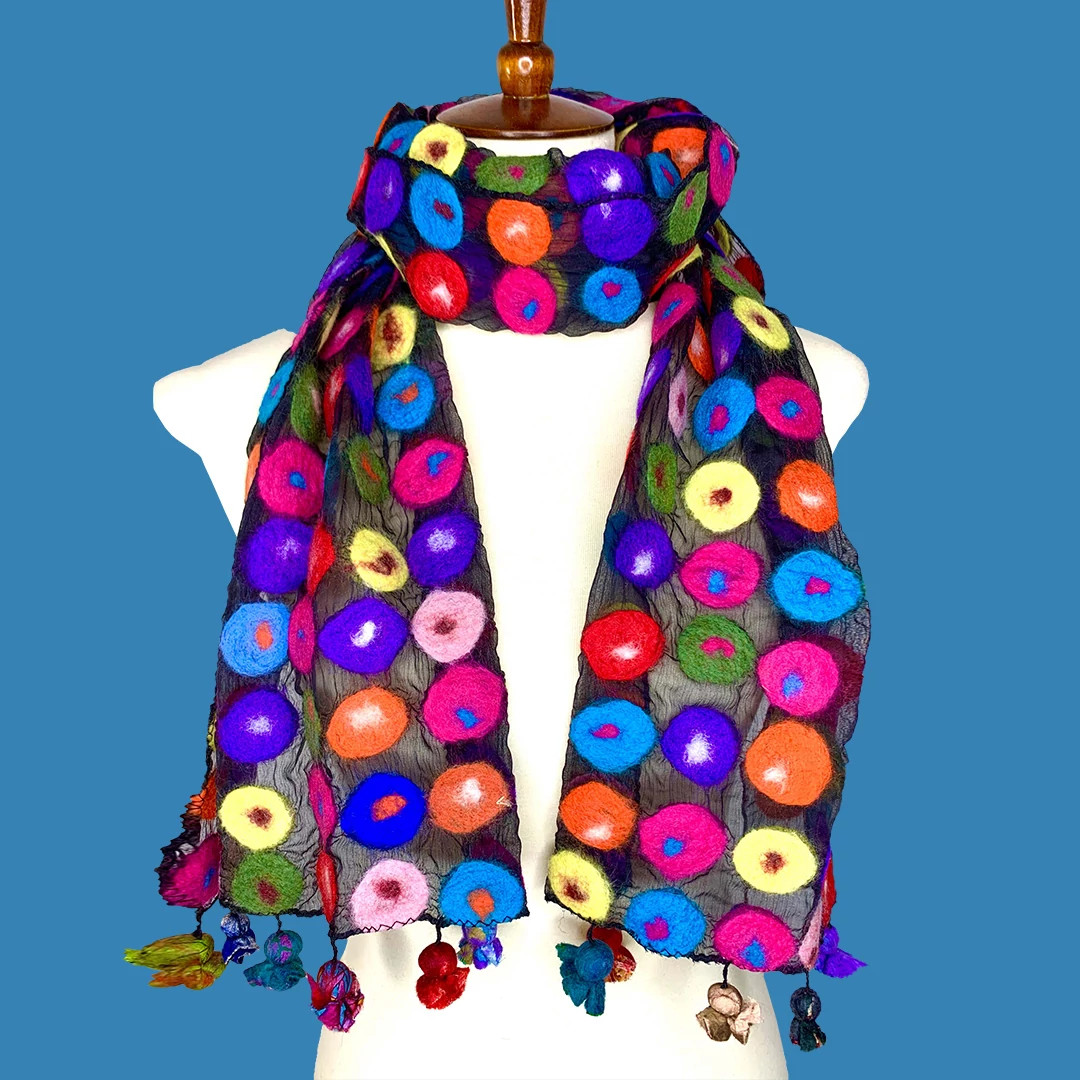 Colorful embroidered scarf with bright circular patterns draped over a white dress-form mannequin