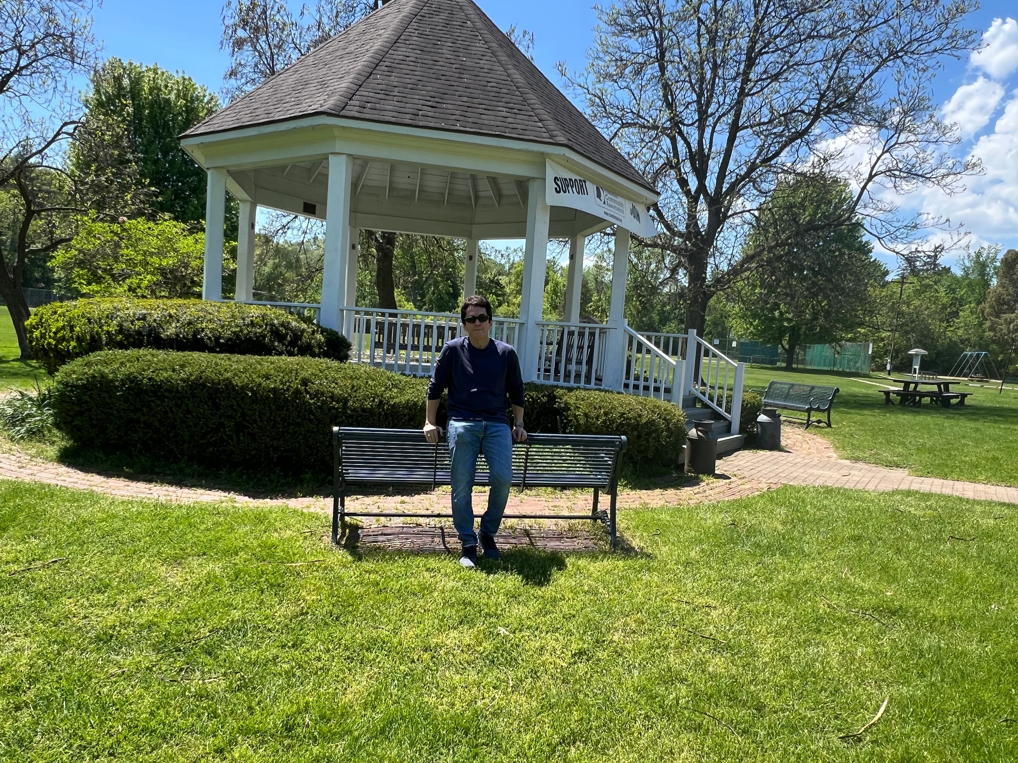 Mitch Albom standing in front of a bench nearby a large gazebo at Franklin Park