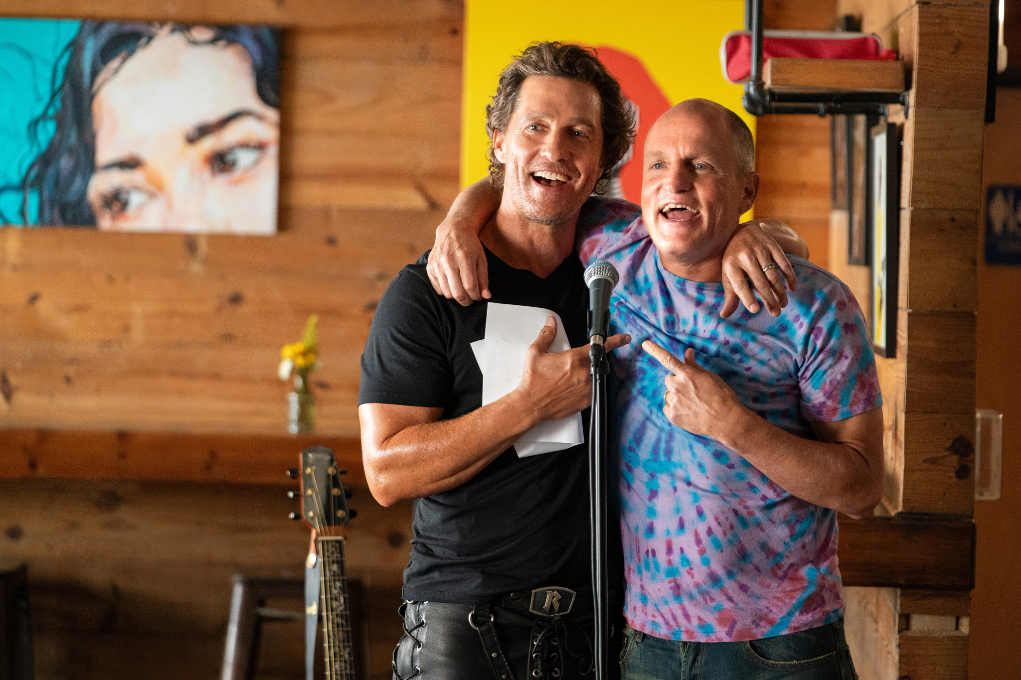 Matthew McConaughey and Woody Harrelson stand together at a microphone in the television show, "Brothers."