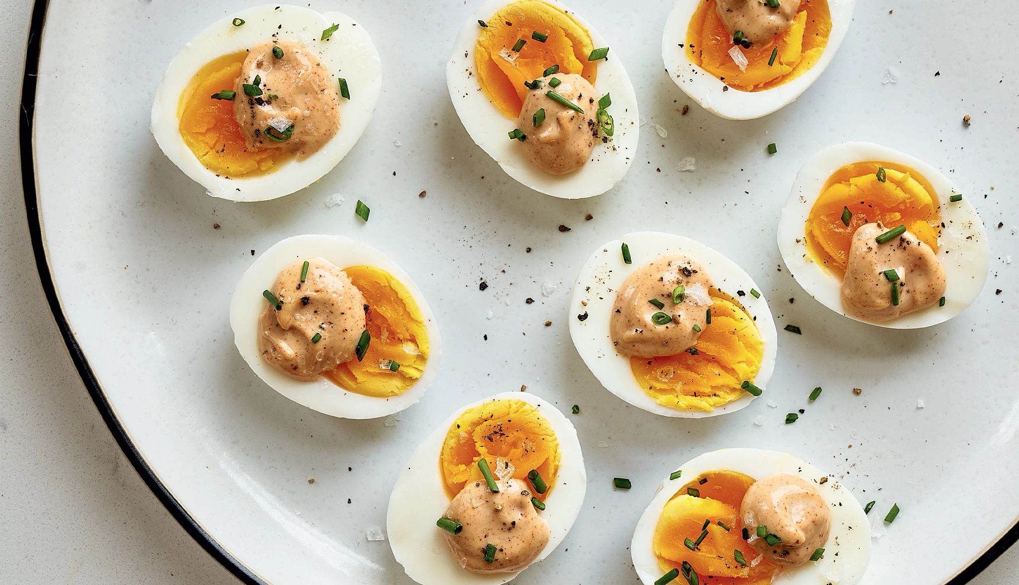 Hard-boiled eggs with dijon mayo Eight halves of hard-boiled eggs on plate with a dollop of dijon mayo on each one