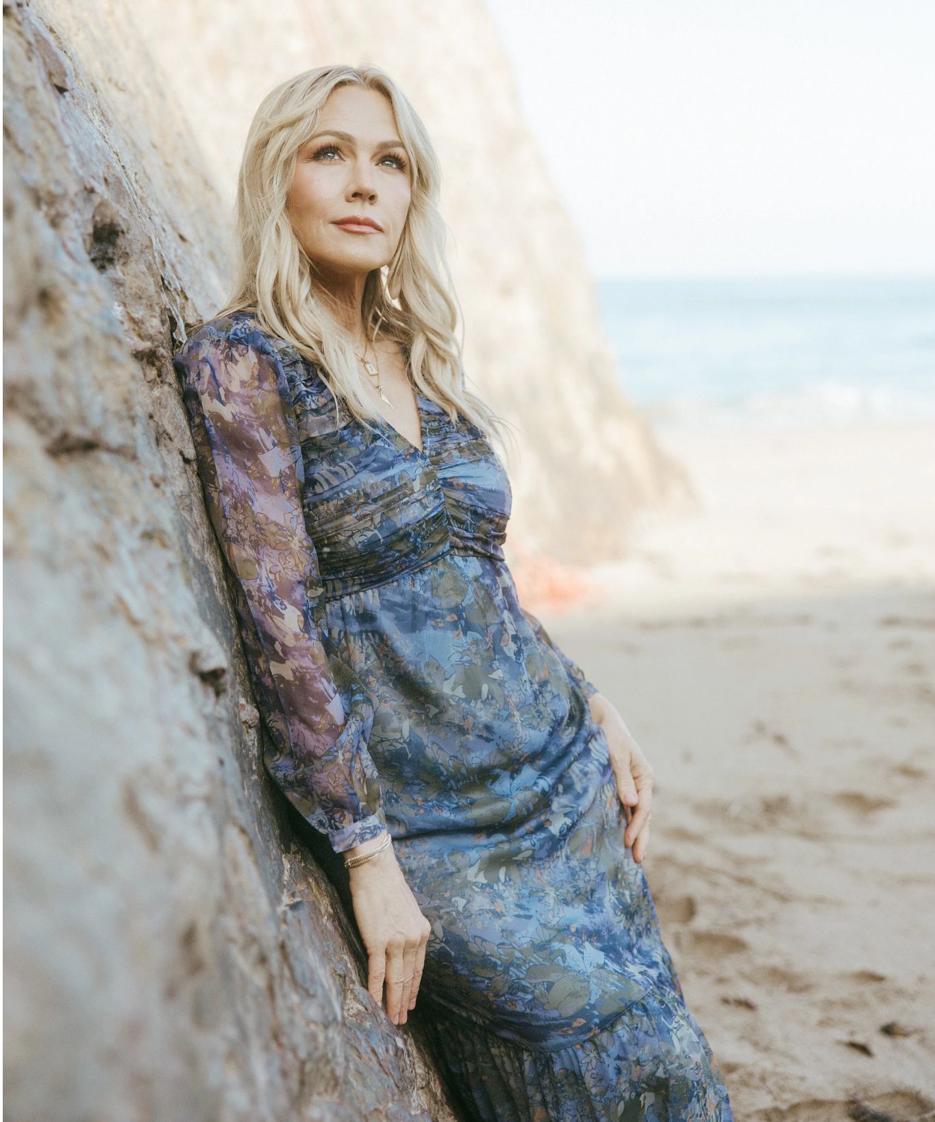 Jennie Garth runs fashion line, Me by Jennie Garth Jennie Garth in dress leaning against rocks on beach