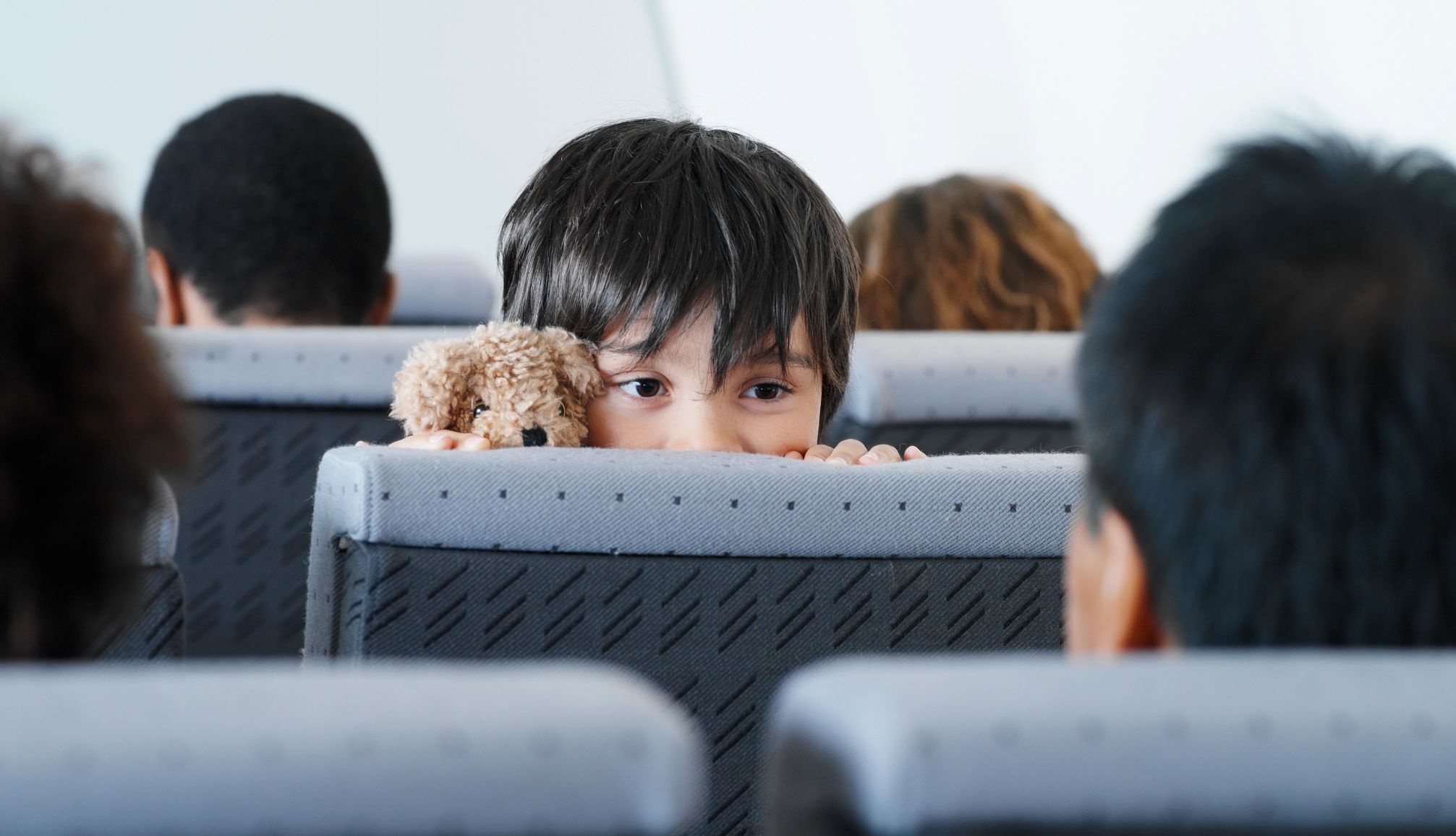 young child looking over the back of an airplane seat