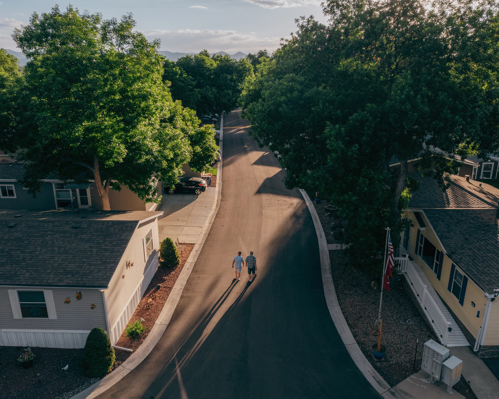 Vista aérea de la comunidad residencial de Meadowood con dos personas caminando por una calle arbolada.