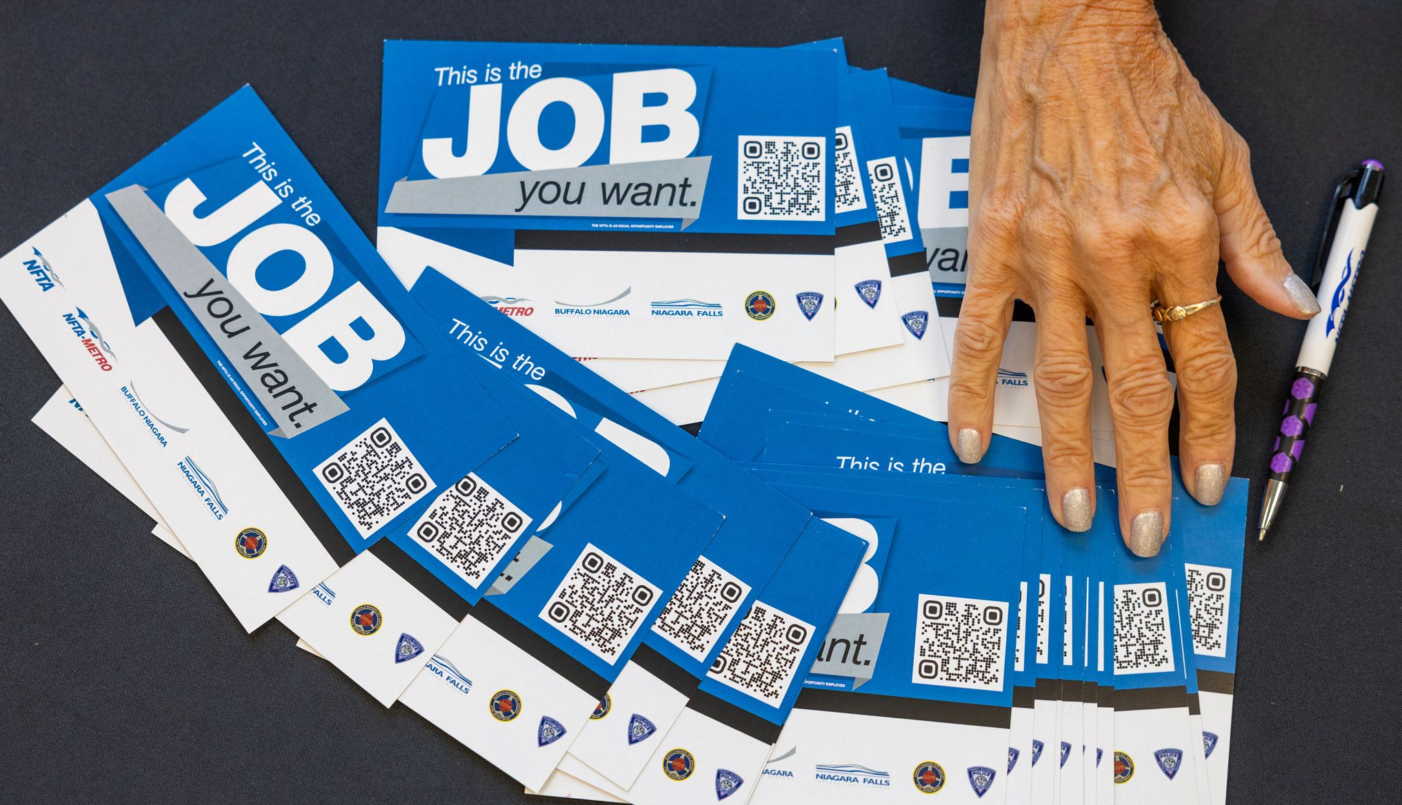 Jobs Numbers a person's hand over job fair fliers on a table