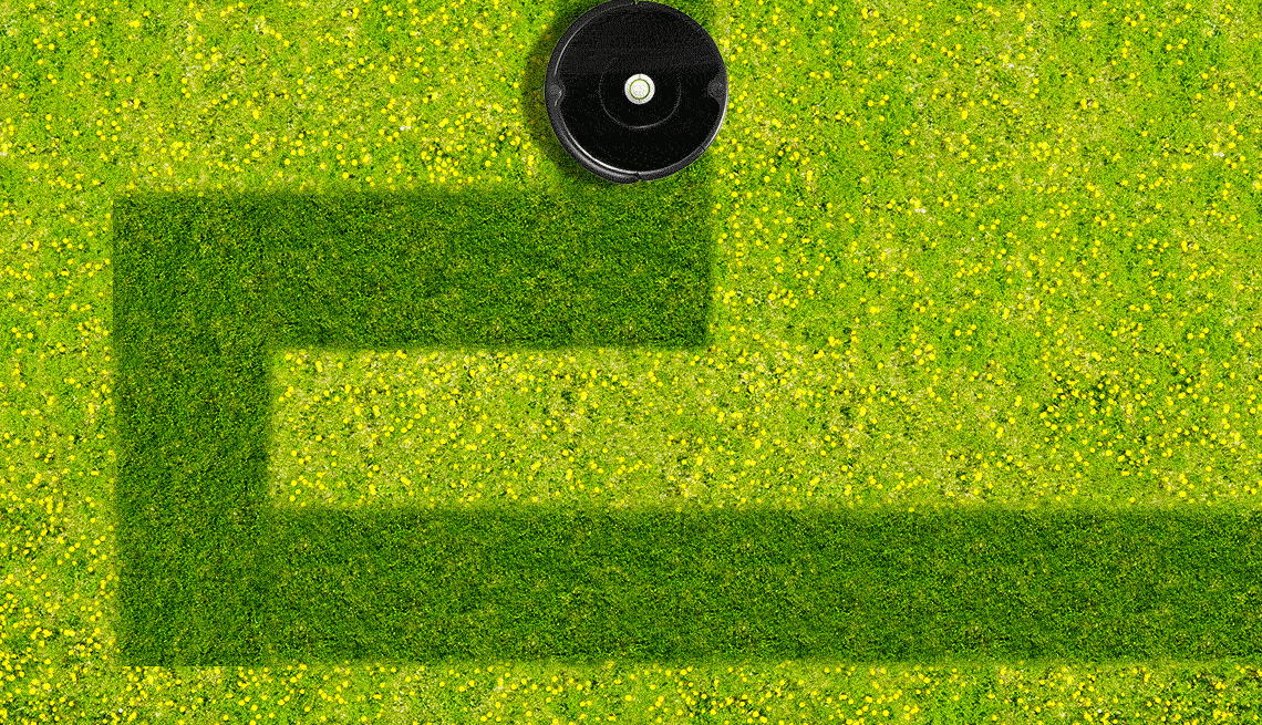 a black robot lawn mower makes a path in a lawn