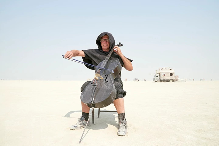 a person playing a cello in the desert