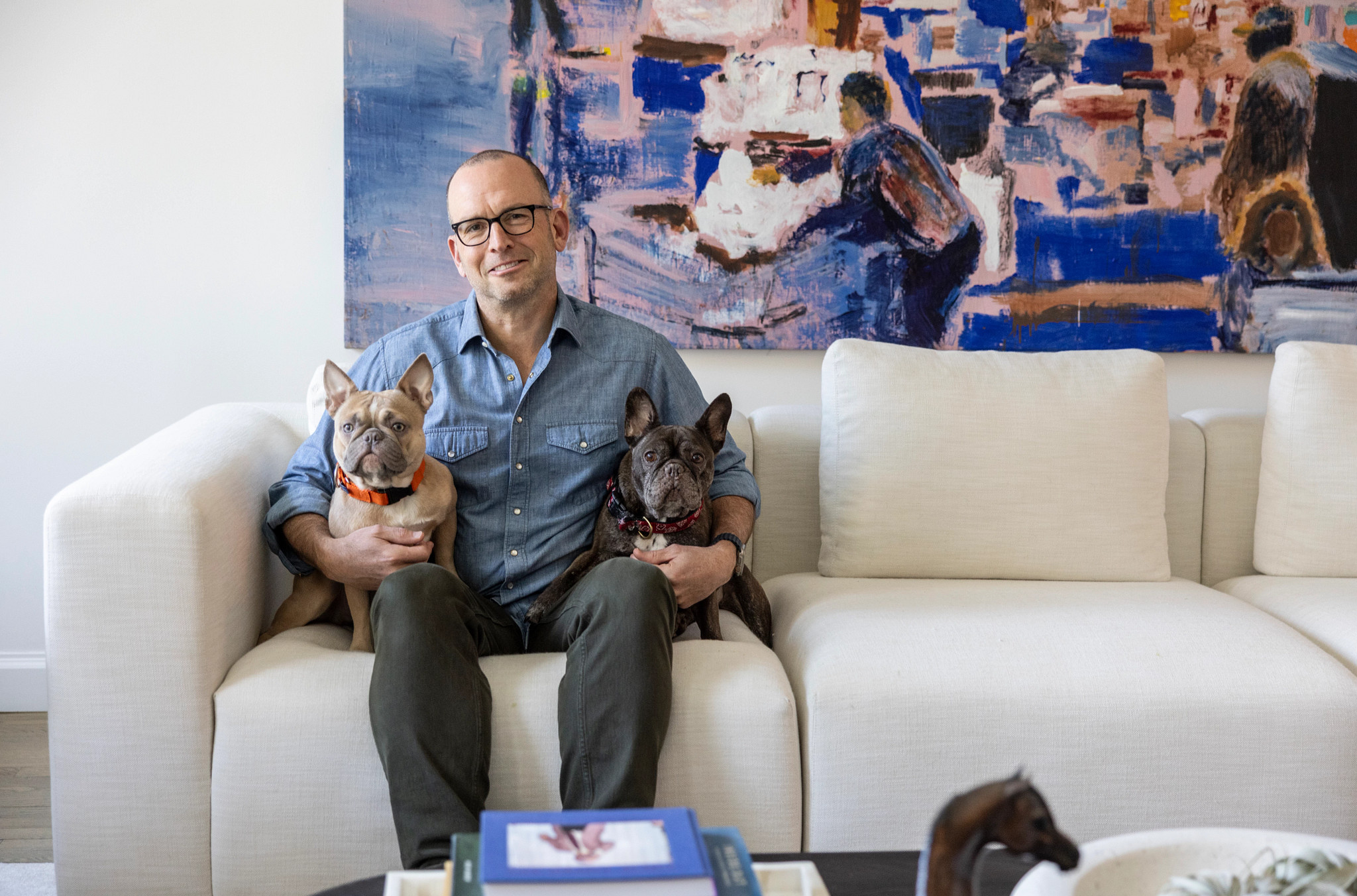 paul ollinger sits on a couch with two dogs