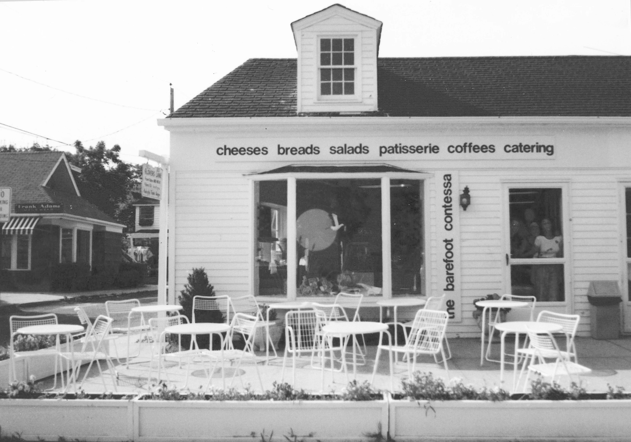 Building that says cheeses, breads, salads, patisserie, coffees, catering, the barefoot contessa; tables outside