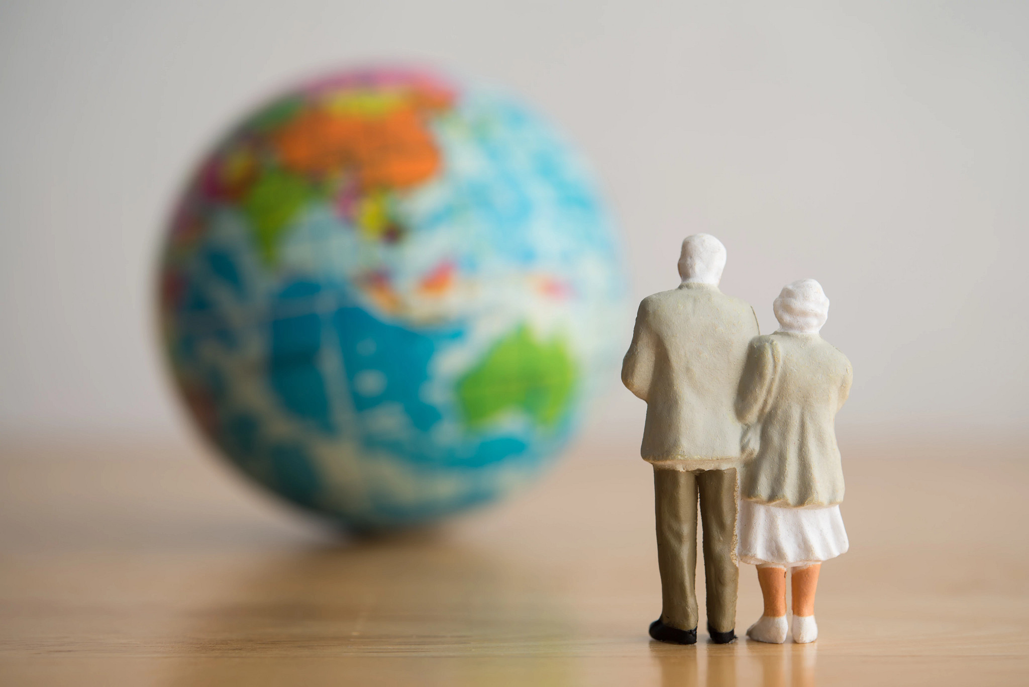 two white haired figurines look at a globe