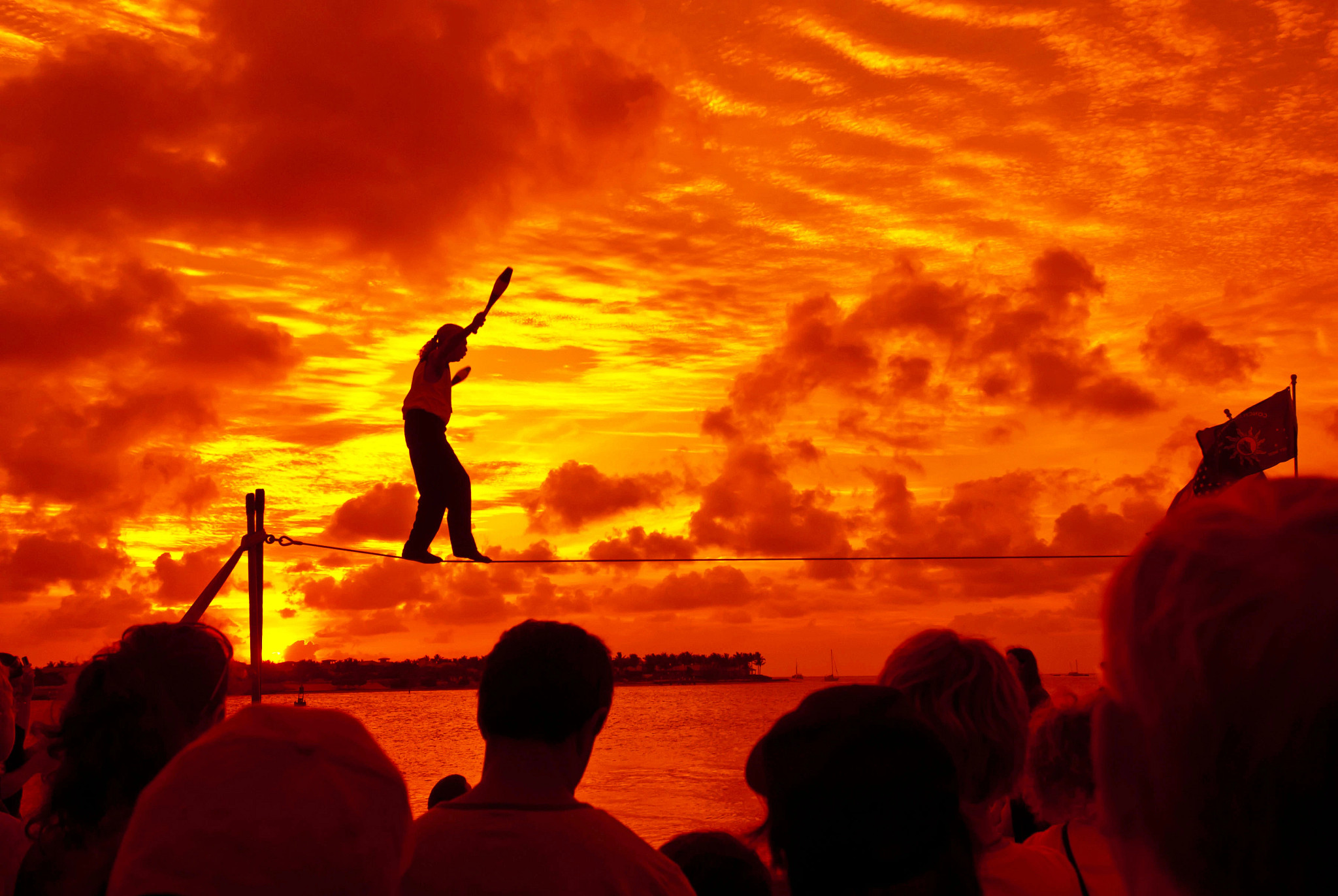 a person walking on a tightrope at sunset in front of a crowd