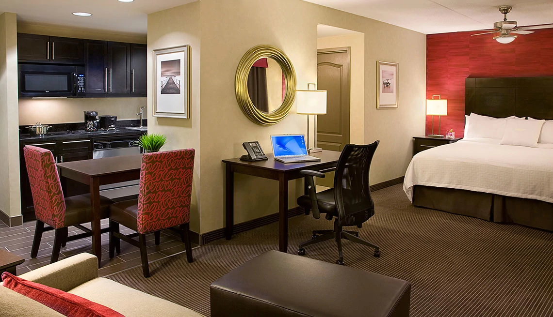 hotel suite room with desk and bed against red wall and door showing