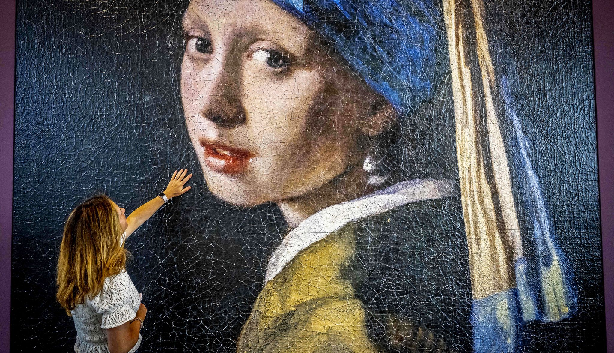 Popping into a gallery or museum to take in an original piece of art, like Johannes Vermeer's painting "Girl with a Pearl Earring," activates memory areas of the brain A woman touching a picture of Johannes Vermeer's painting "Girl with a Pearl Earring"