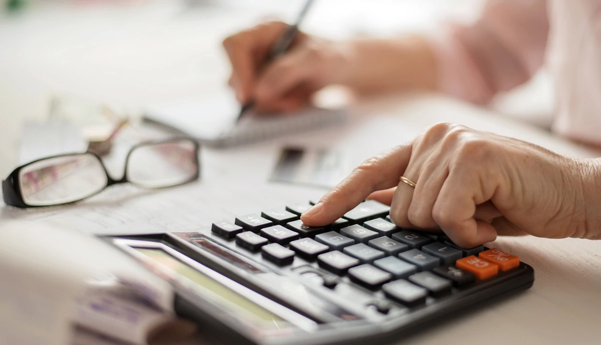 Close up of hands typing on calculator