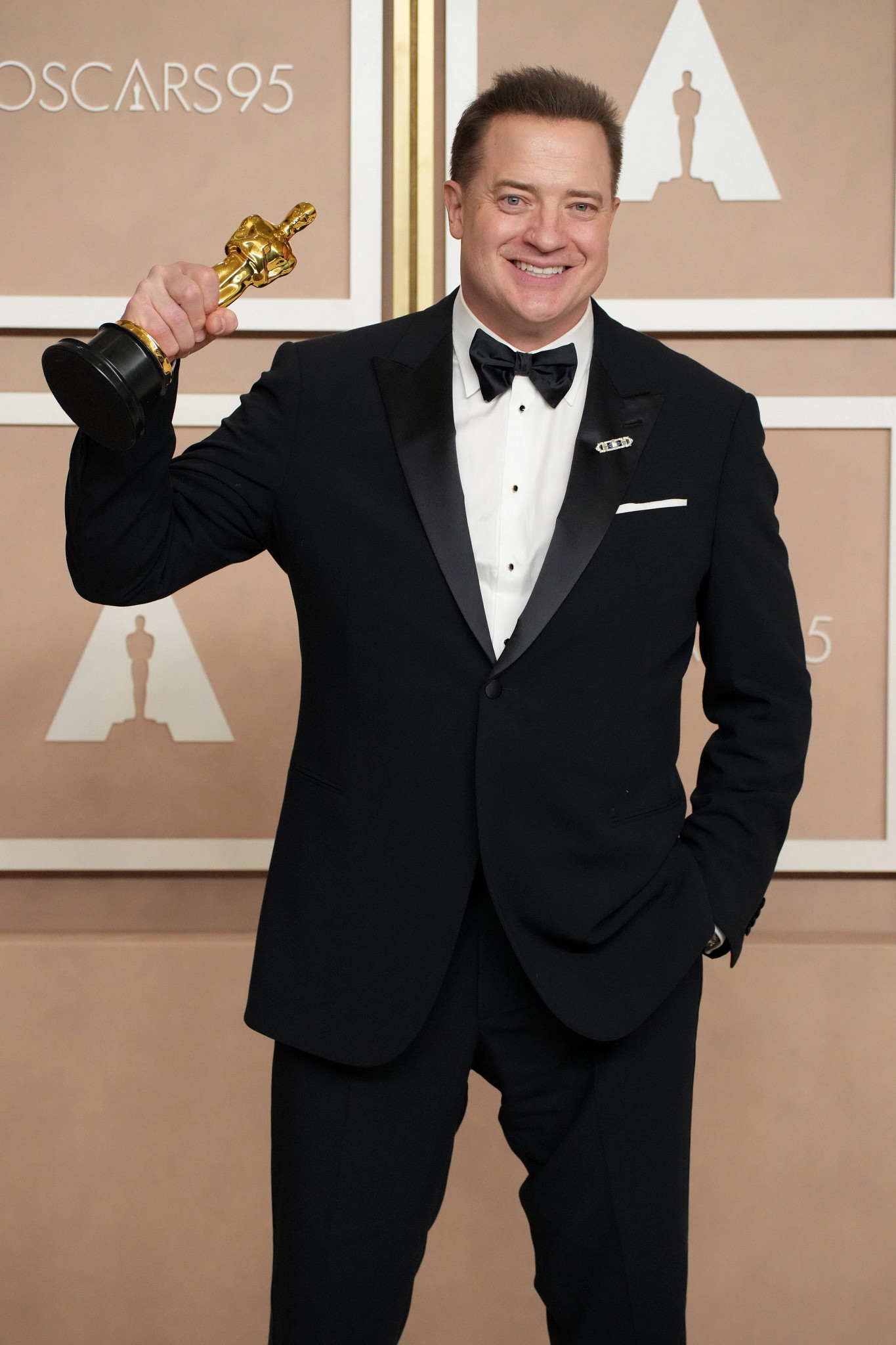 brendan fraser smiling, holding his best actor oscar statue