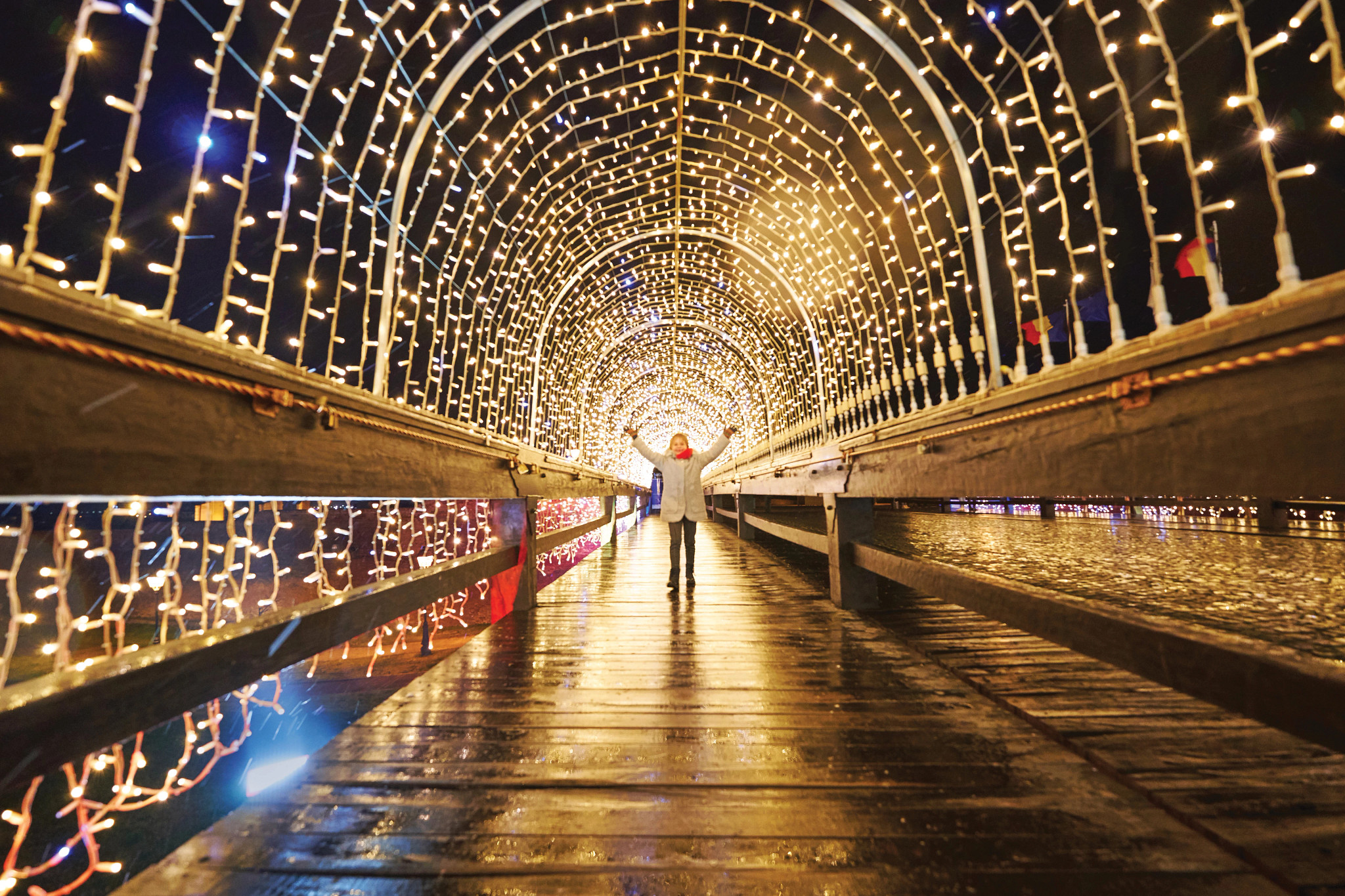 Girl admiring the tunnel with holiday lights, public lighting for the Christmas and New Year holidays