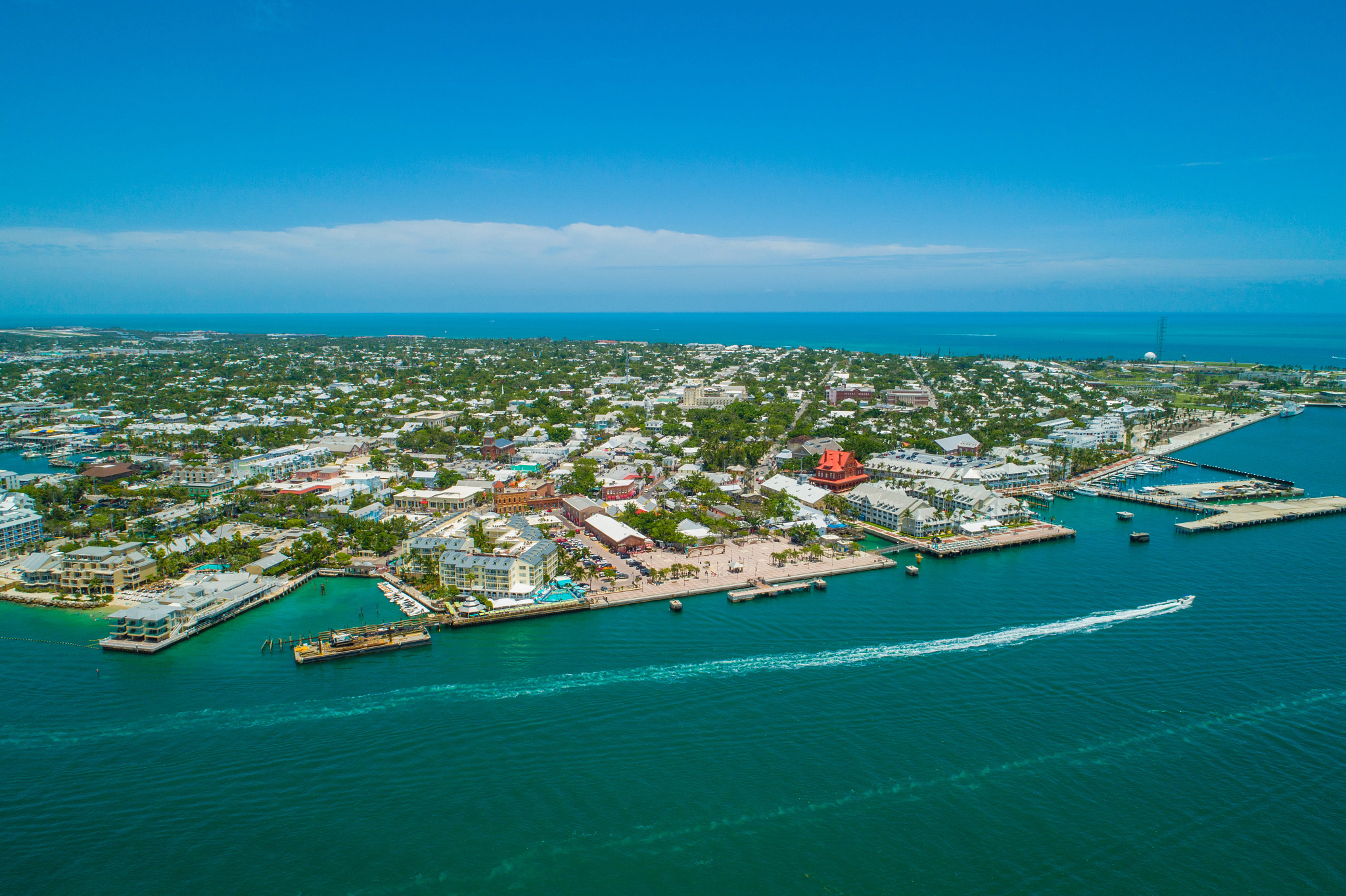 A waterfront coastal town with marinas, boats, residential neighborhoods and bright blue ocean waters.