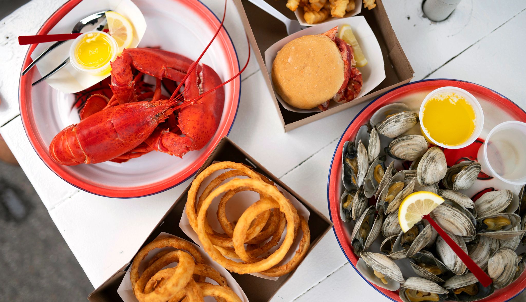Nostalgic Beach Getaways a closeup shot of lobster, onion rings, a burger and clams