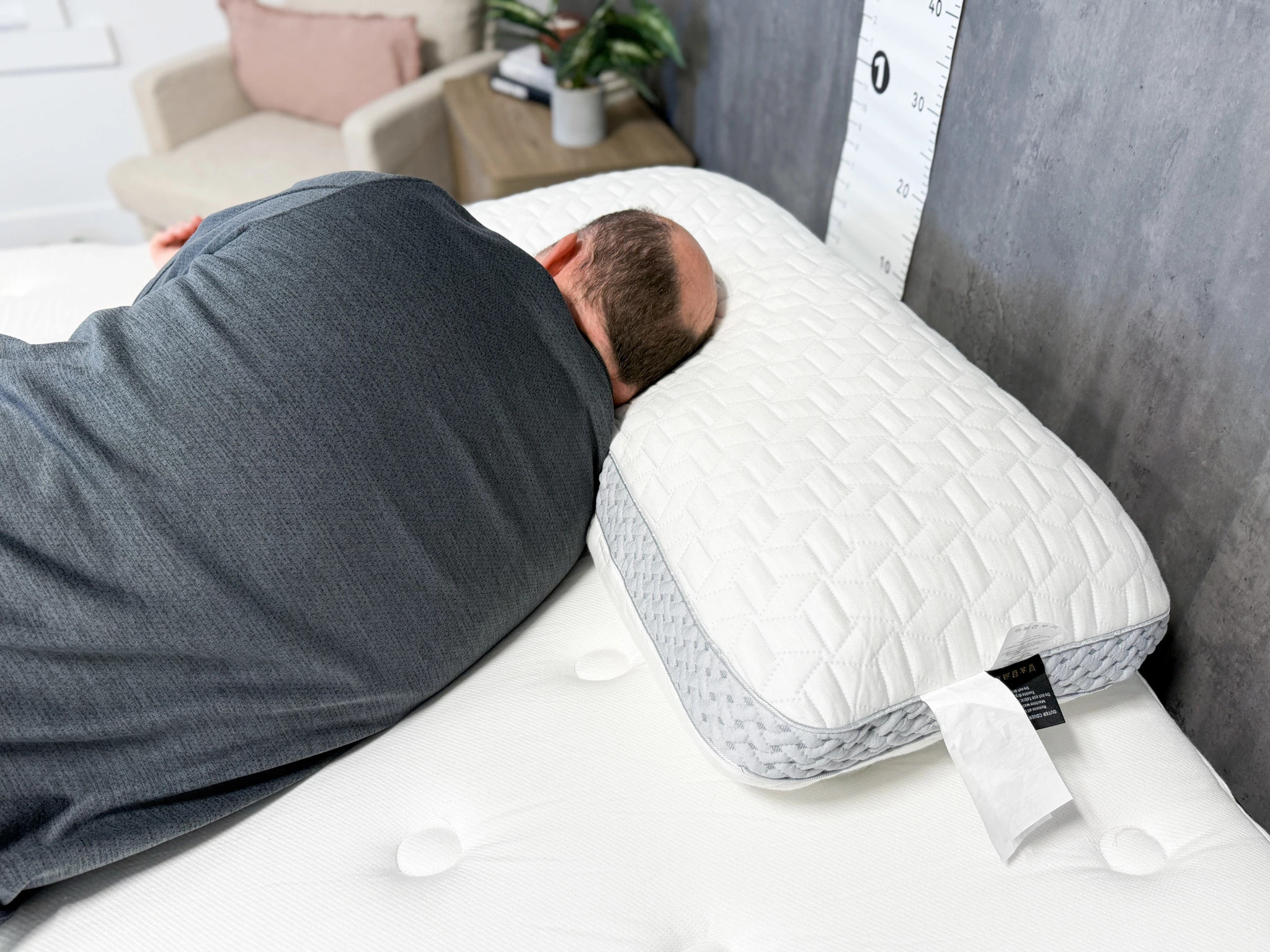 A man lies on his side on a mattress with his head on a Luxome LAYR pillow