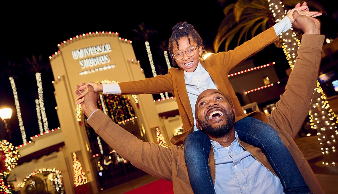 Father and daughter celebrating the holidays at Universal Studios Hollywood with Christmas lights in the background