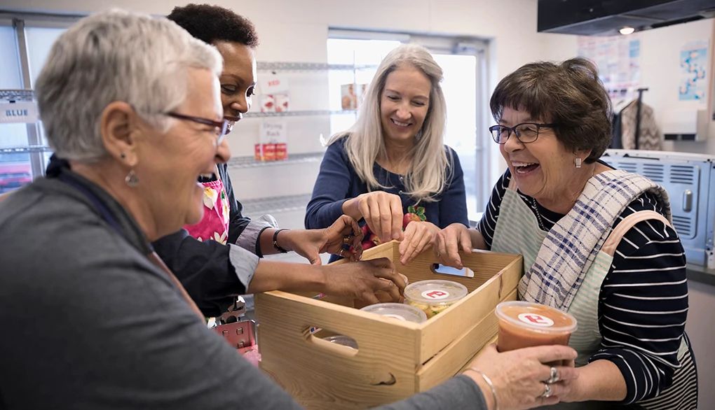 People who are generous with others feel less harried Female volunteers packing soup containers into crate in soup kitchen