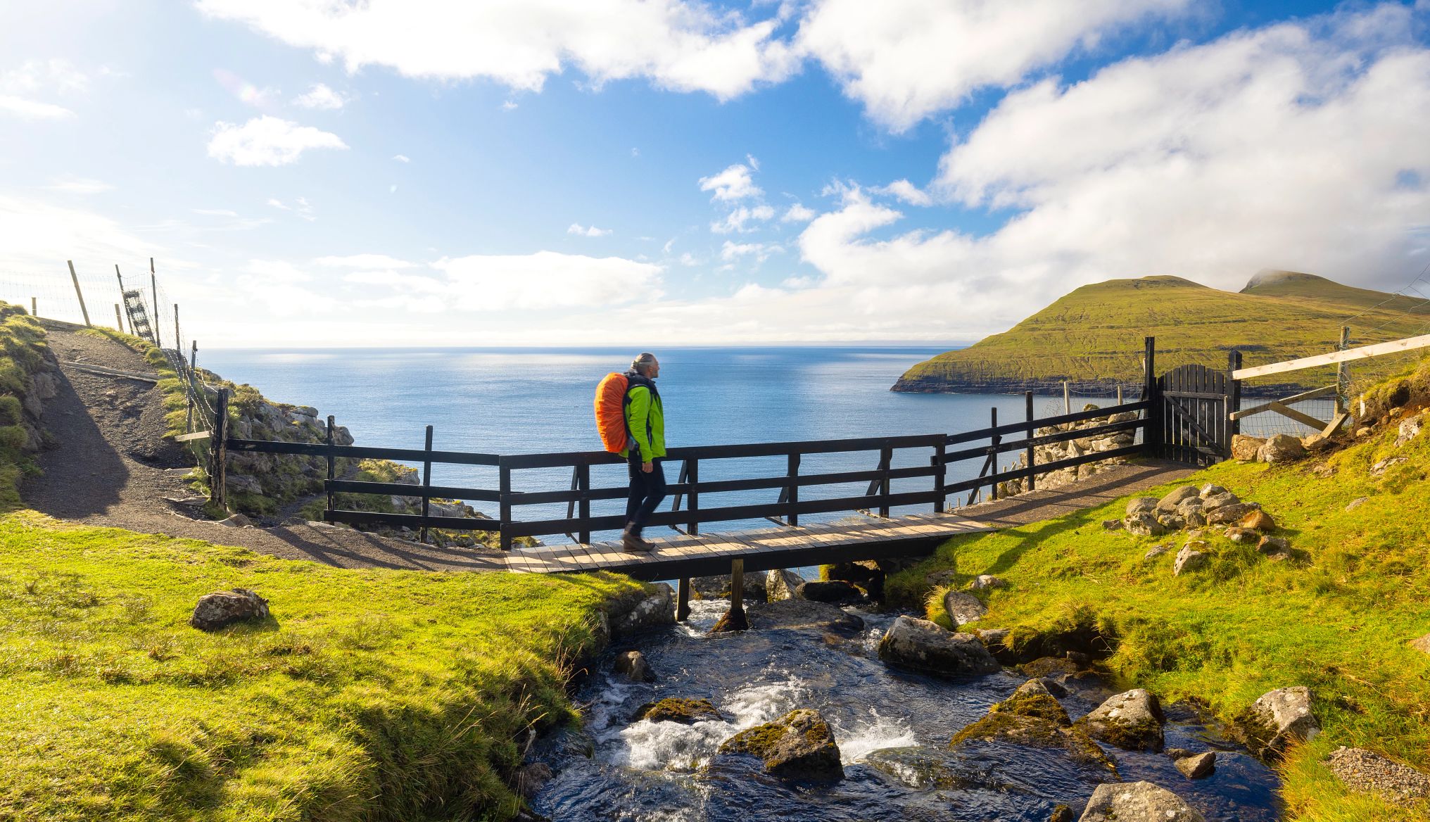 Una persona camina por un puente de madera en Sandavágur, en las Islas Feroe