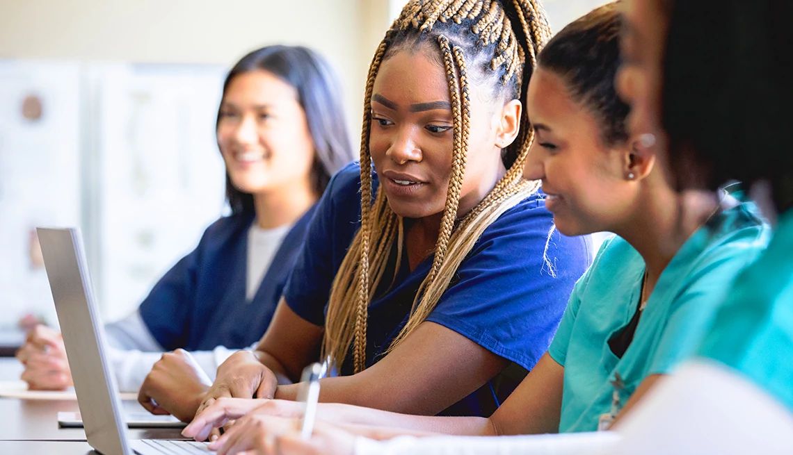 AARP is awarding grants for projects that help strengthen the nursing workforce Group of three nurses in a class looking at a laptop