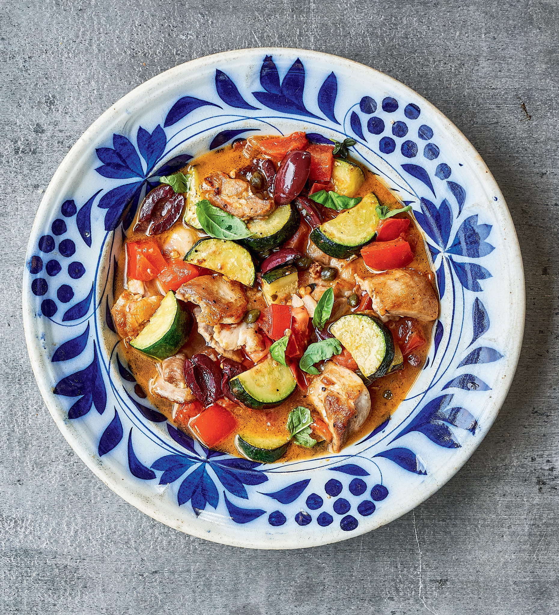Stew made of chicken, olives, capers, garlic, zucchini and tomatoes in a bowl