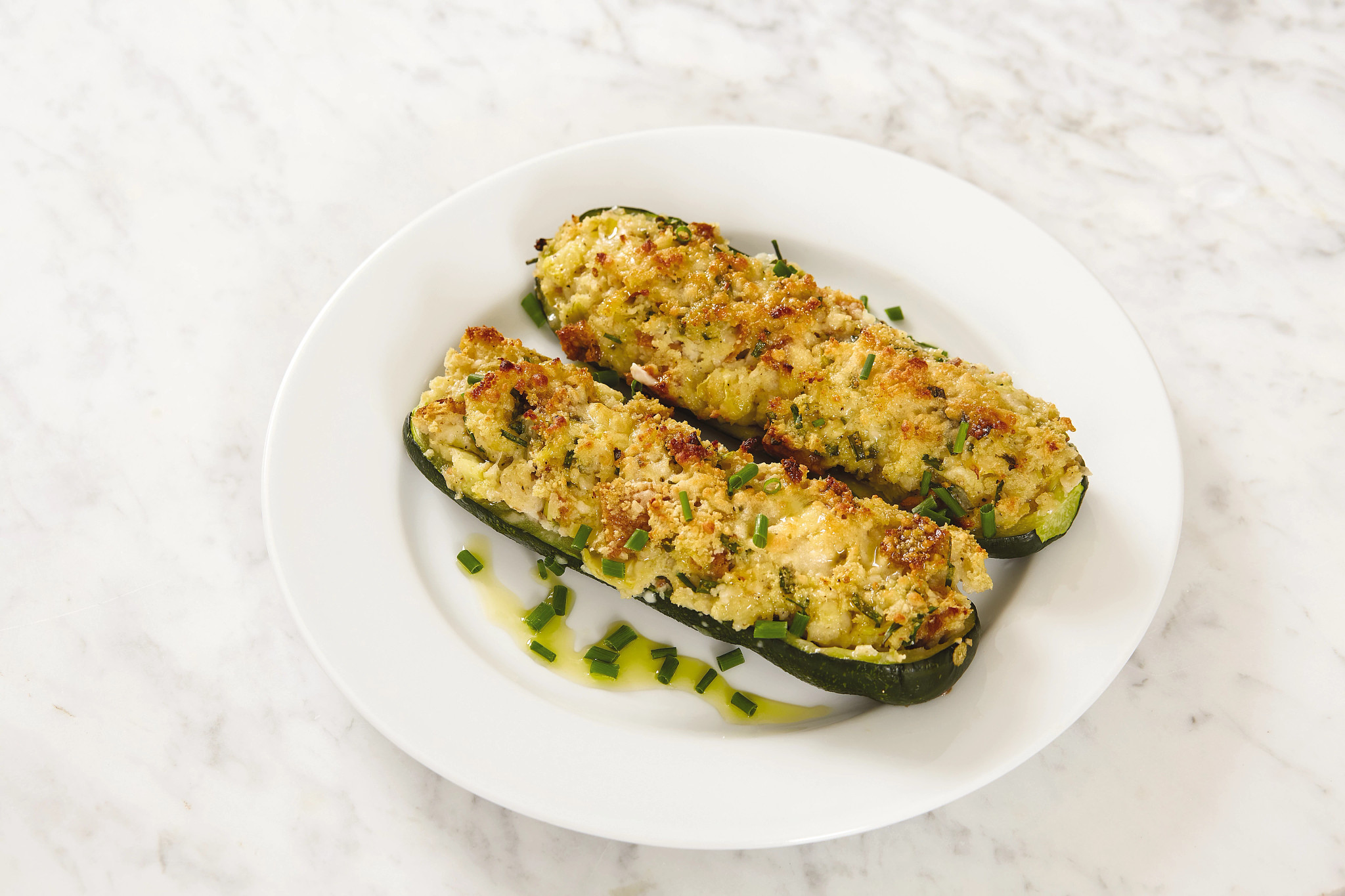 Two herb-stuffed zucchini boats on a plate