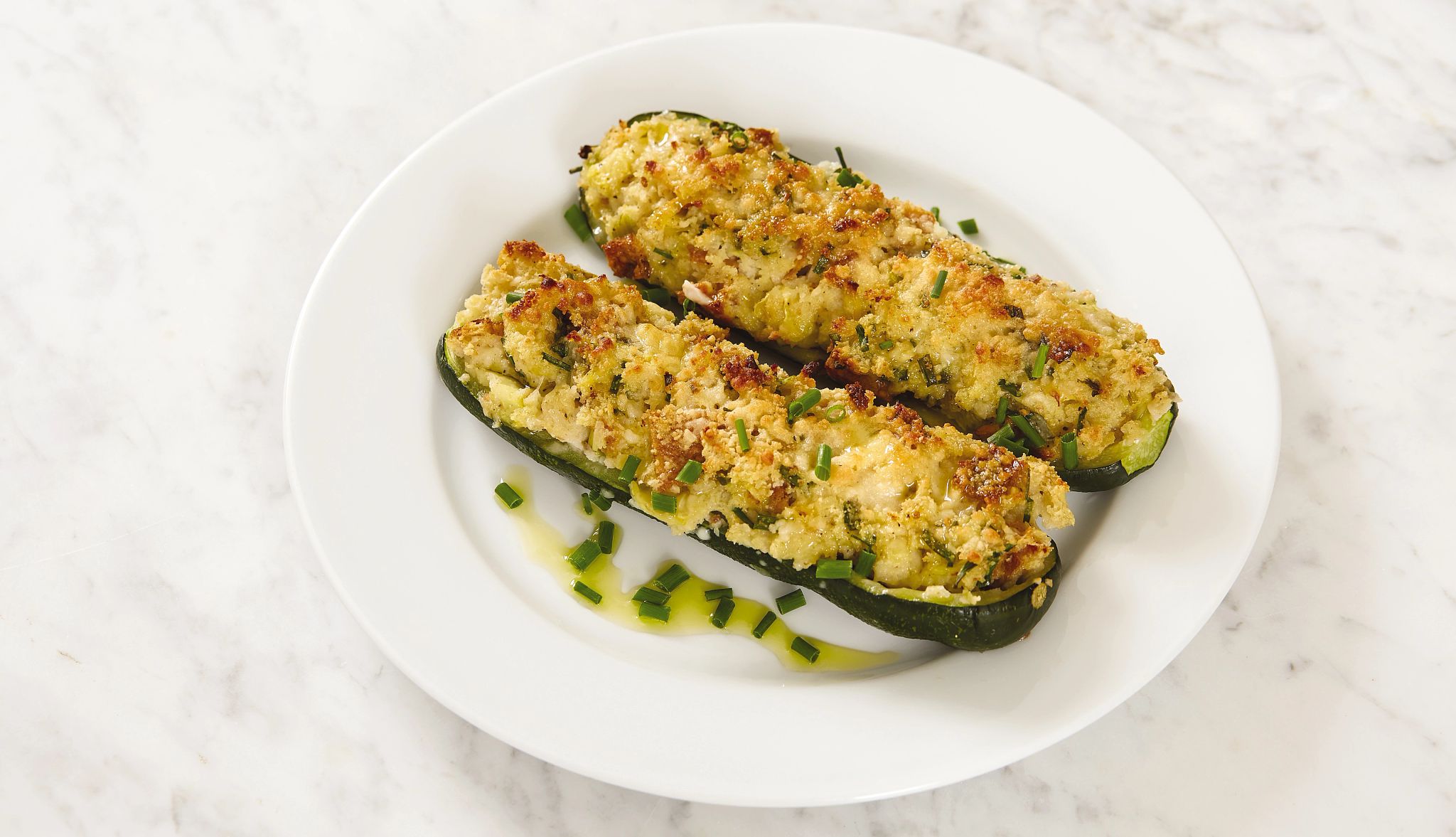 Herb-stuffed zucchini boats recipe Two herb-stuffed zucchini boats on a plate