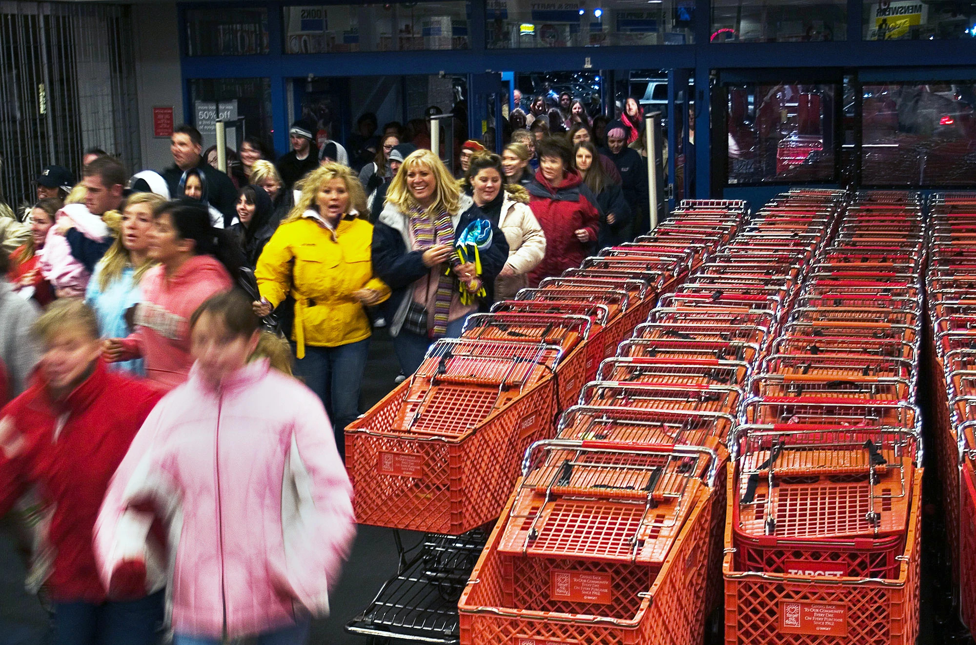 Multitud de compradores pasando junto a carritos de compras rojos en un Target